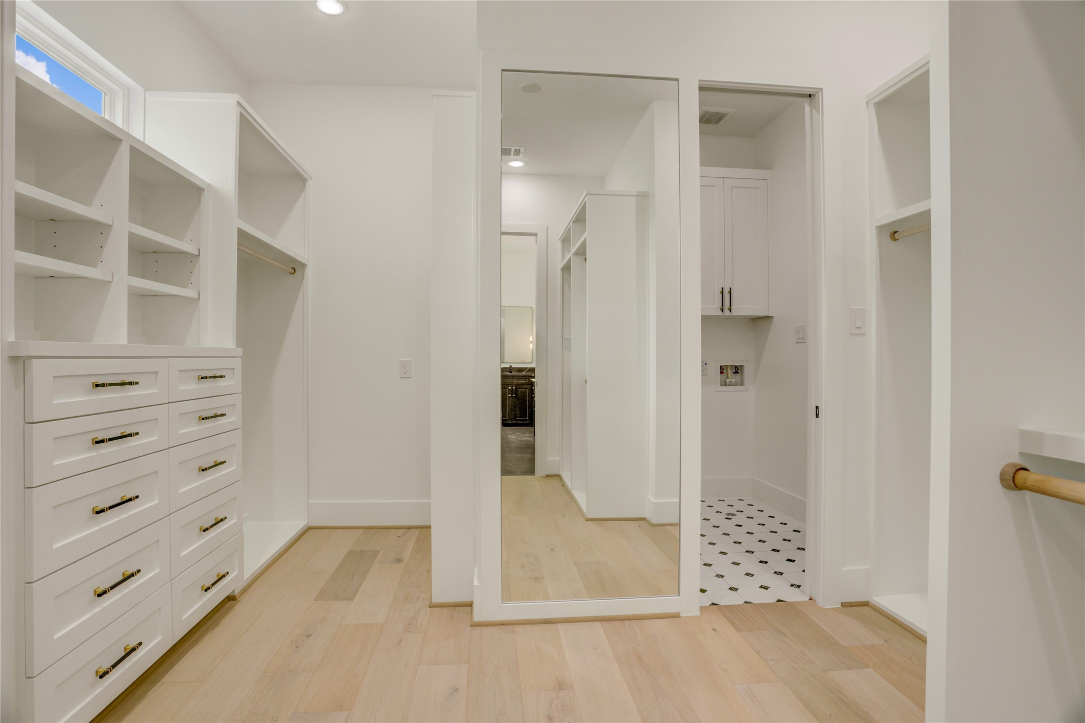 The primary closet, complete with built-ins and a full-length mirror, also allows for direct access to the utility room.