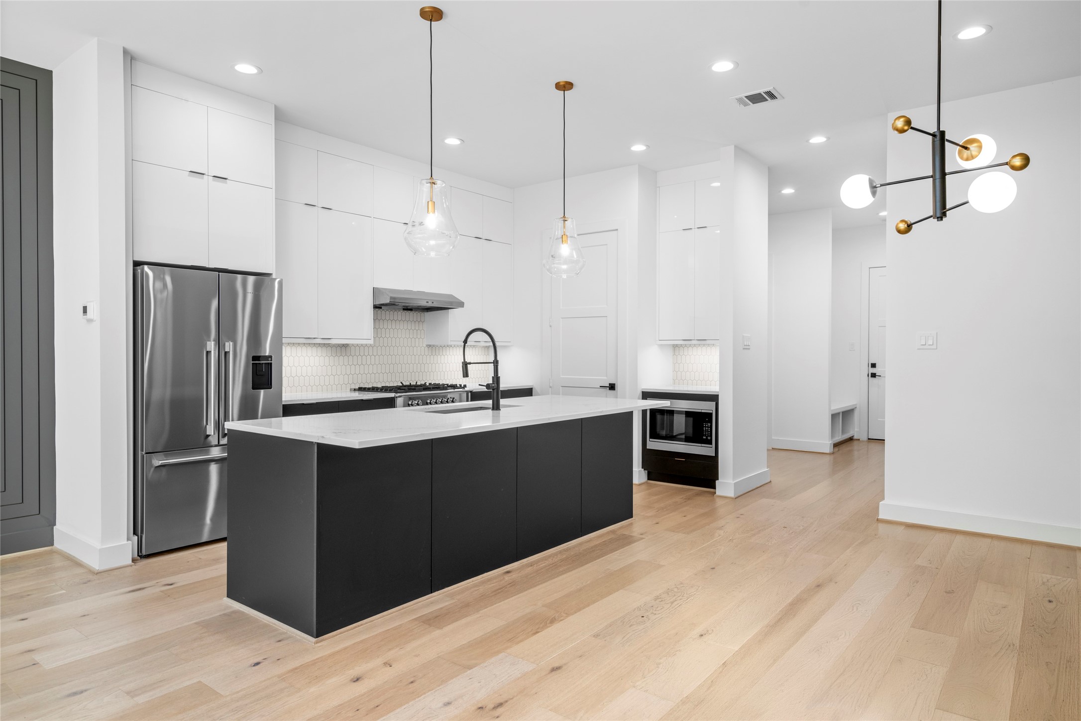 Another view of the kitchen with the microwave in sight and the pantry door on the left. Under counter lighting throughout.