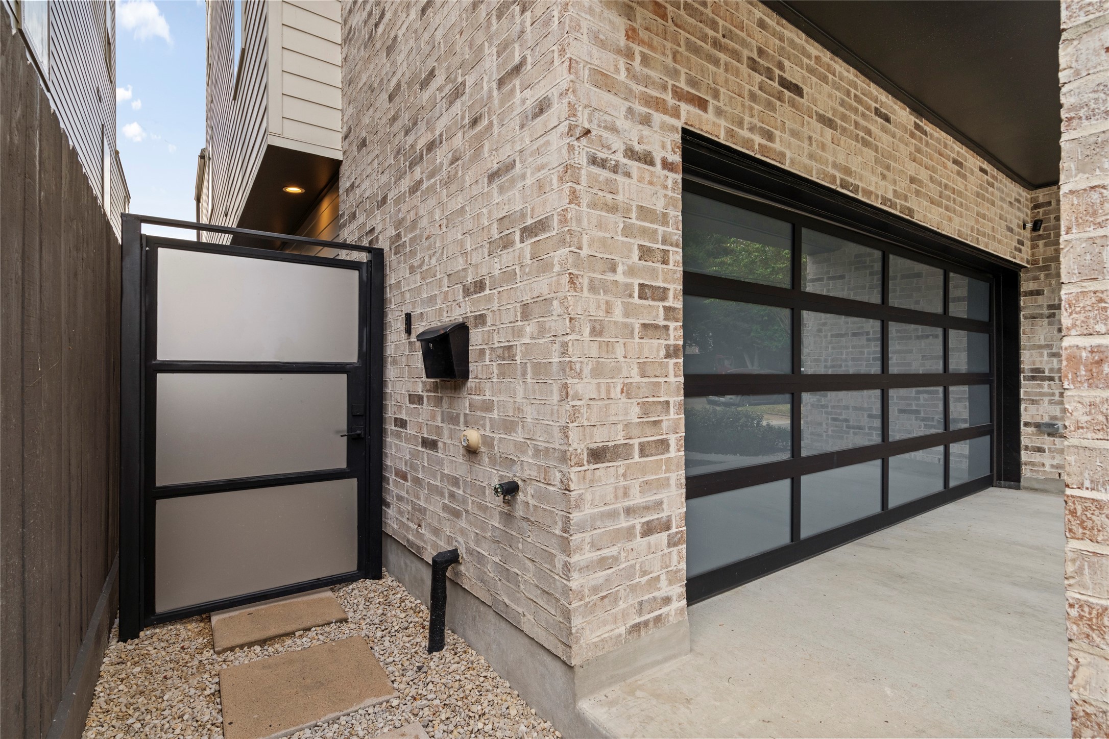 Privacy iron pedestrian gate and 16 ft. garage door with glass.  Sellers have added tint to the windows.