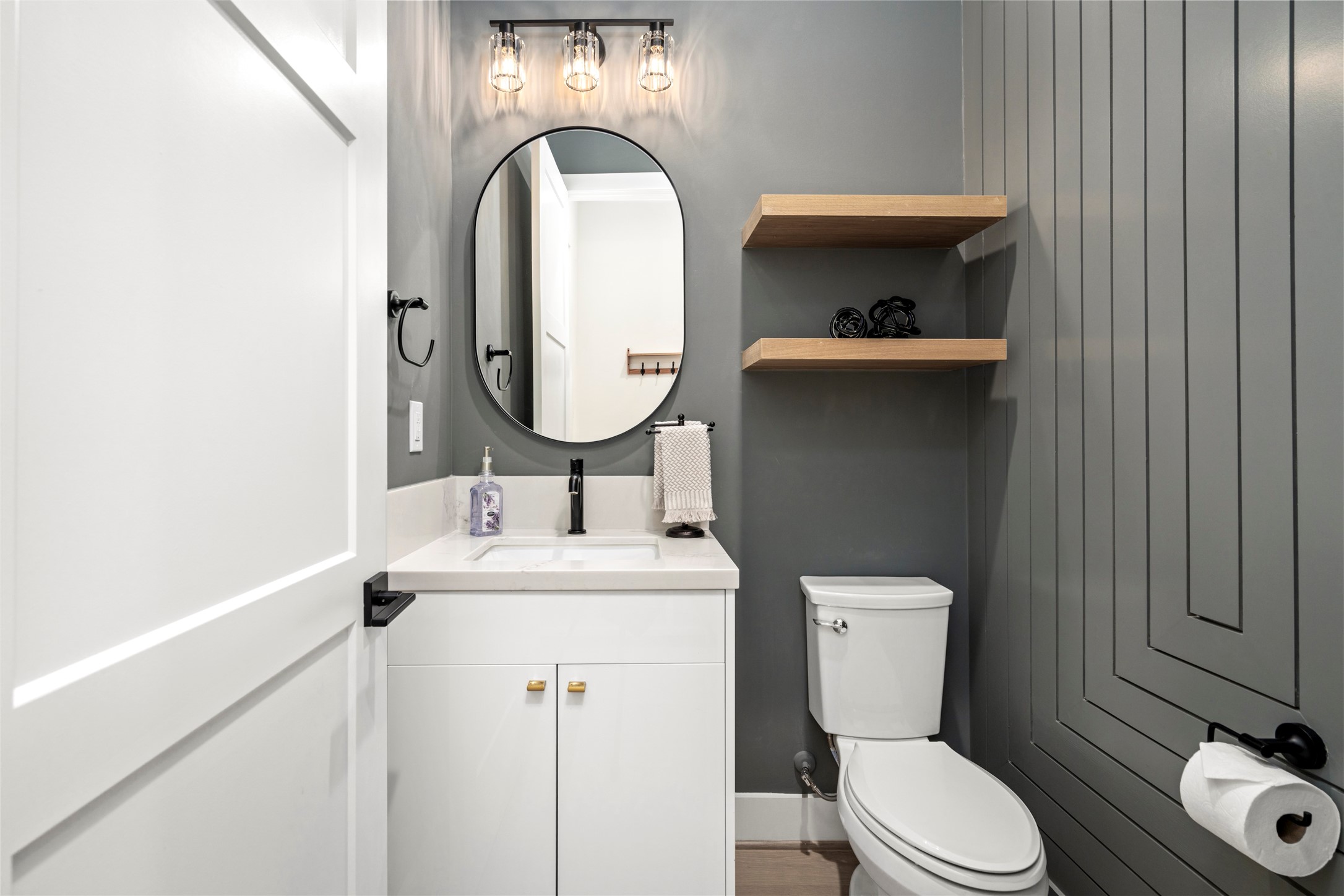 Half Bath/Powder Room has custom designer millwork, paint, lighting and fixtures.  Located directly as you come in from the garage.