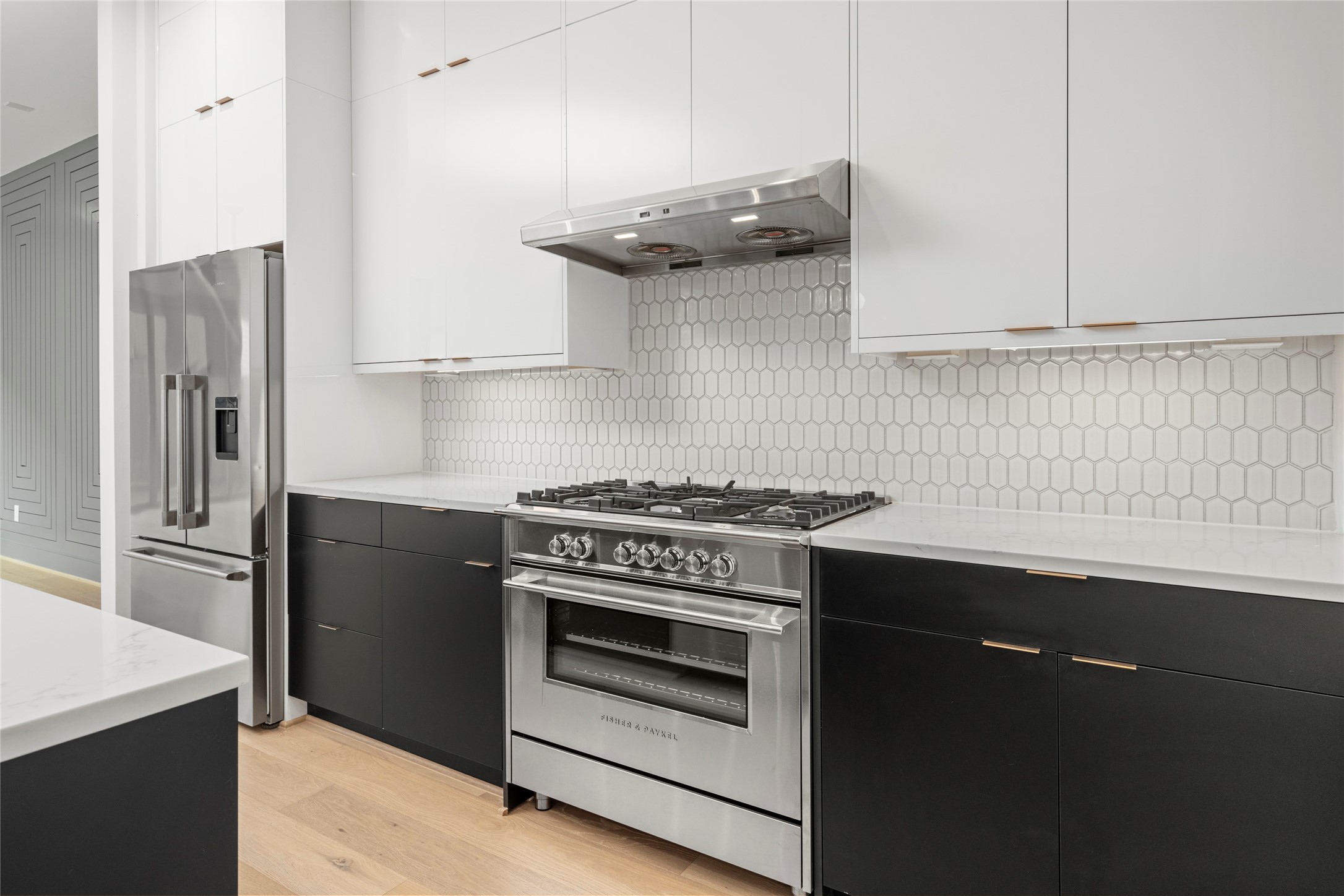 36" Fisher & Paykel free standing range and hood vent, with built in 36" french door refrigerator/freezer with pro handles and internal ice and external water. Gold finish cabinet hardware and soft close cabinets and doors.