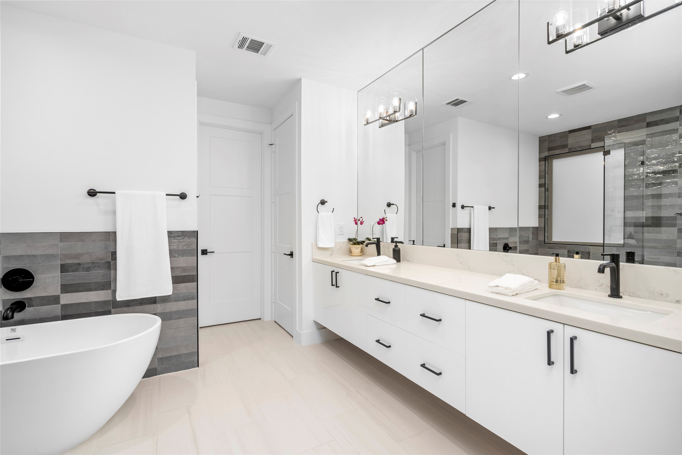 The primary bathroom has a freestanding soaking tub, full wall of mirrors with double floating vanities with quartz counter tops.  So much cabinet and drawer storage.