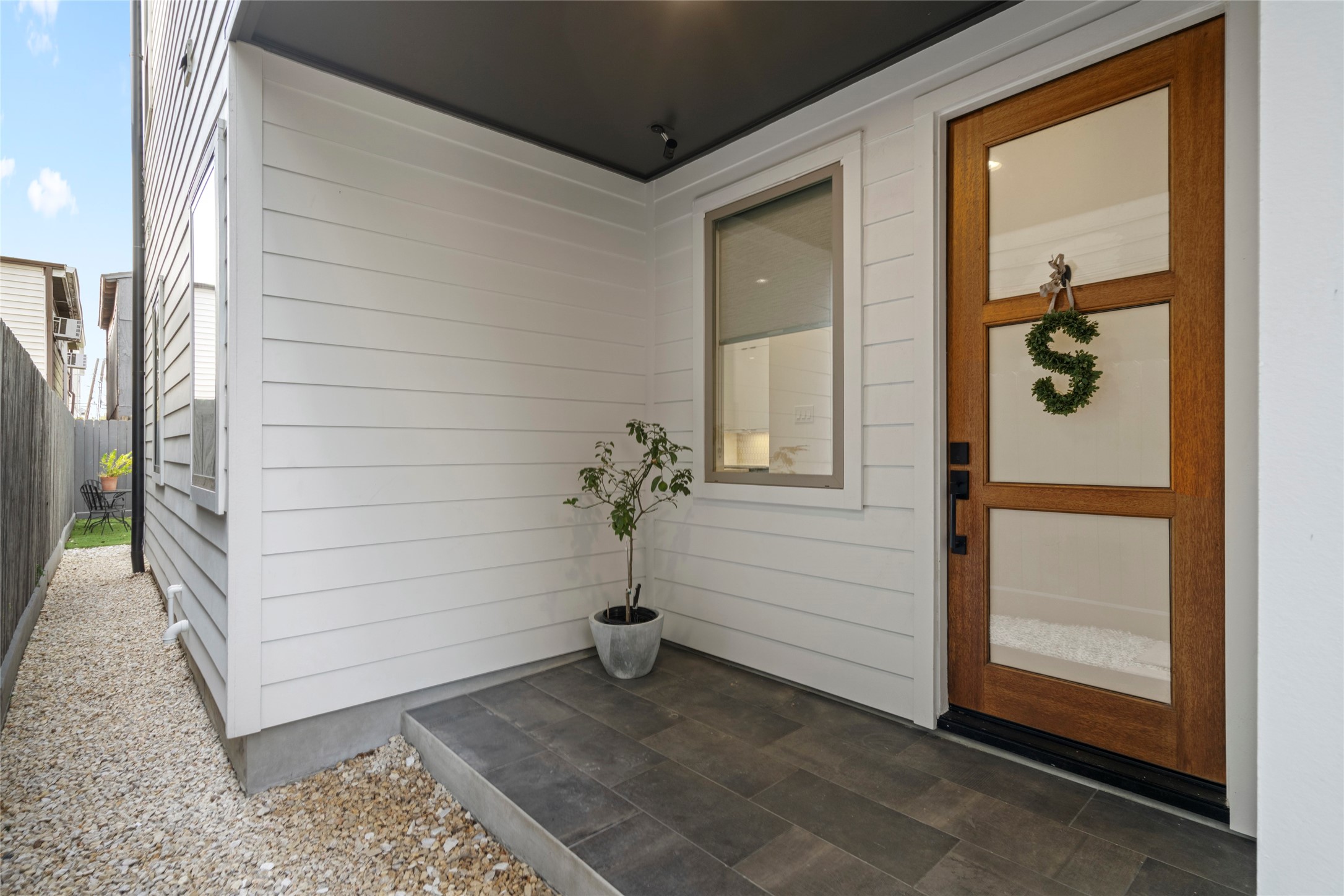 Welcoming covered Entry.  Custom 3-lite mahogany stained front door.  12" x 24" porcelain tile in brick pattern.  Low maintenance crushed limestone side yard.
