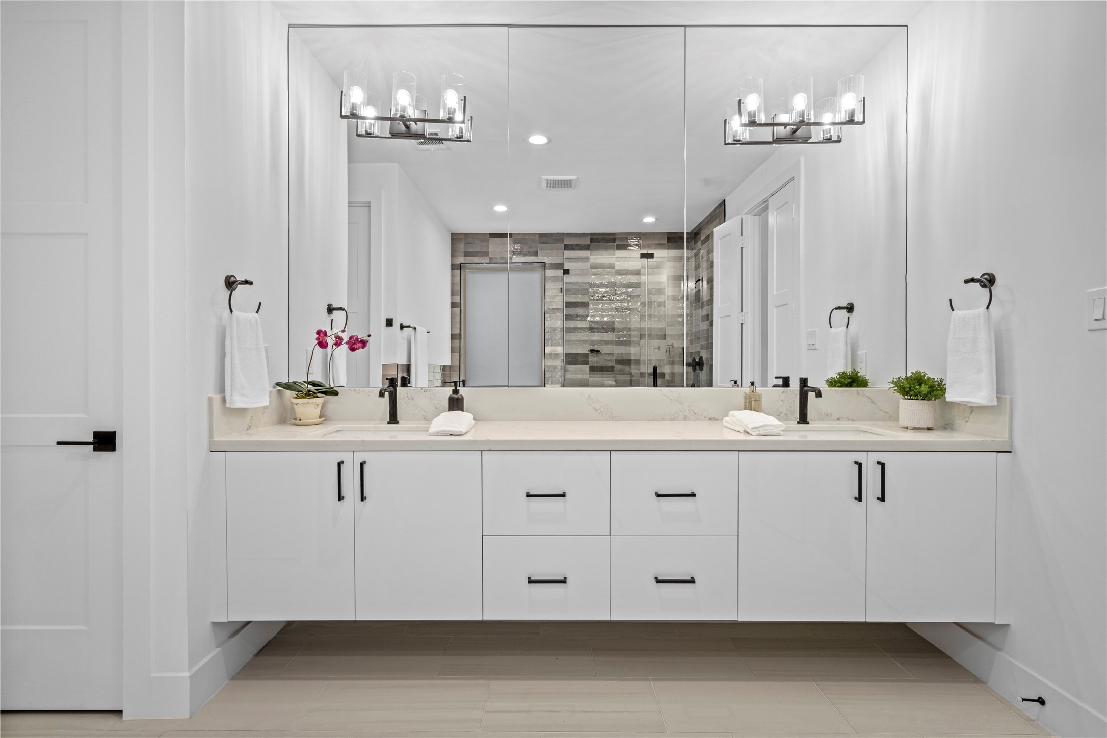 The double vanity has undermount sinks, single lever faucets and triple light sconces.  All fixtures, hardware and bath accessories have matte black finish.