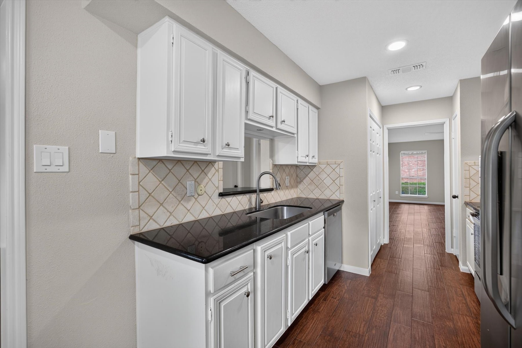 Generously proportioned kitchen with white cabinetry and stainless pulls. Refrigerator stays with home.