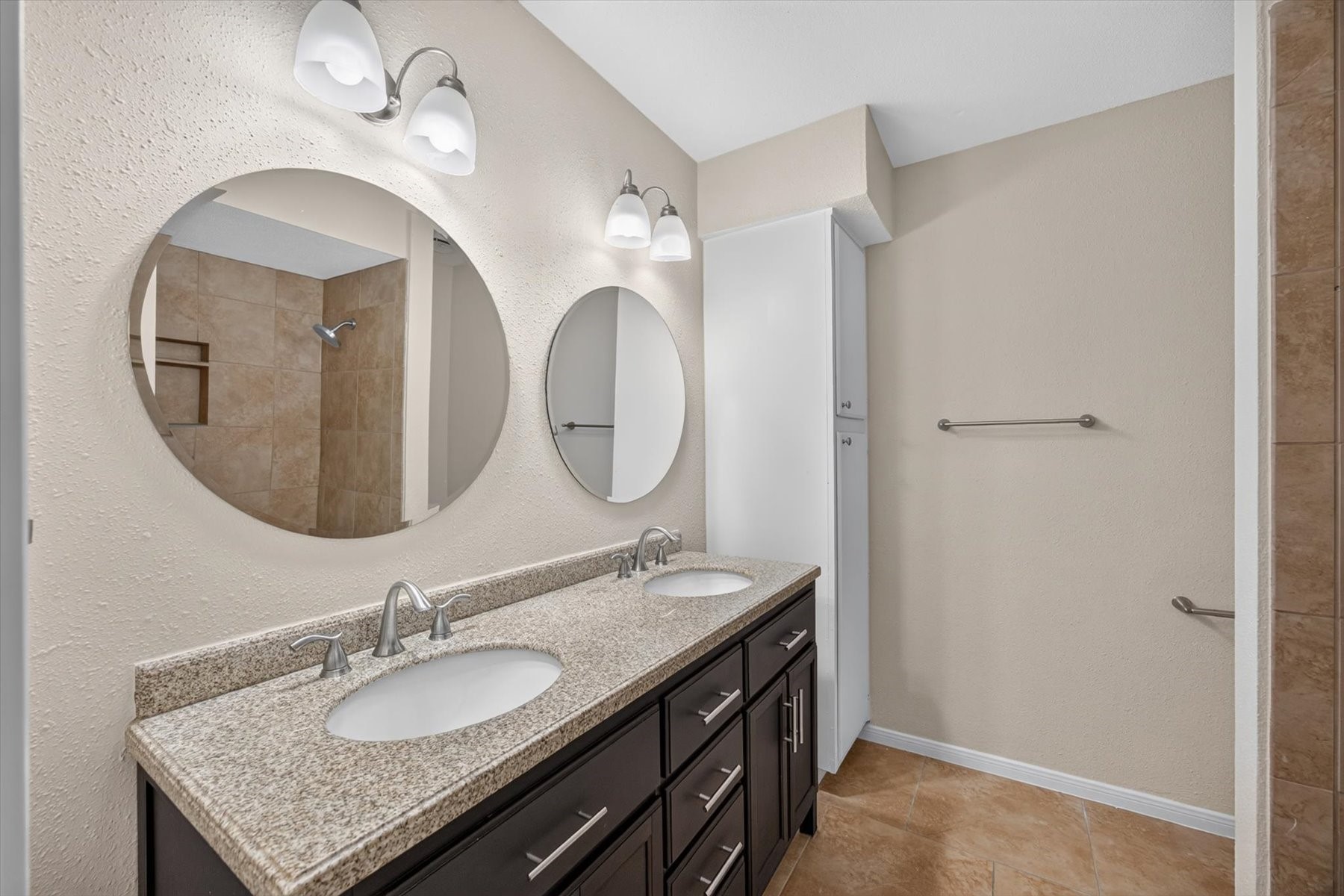 Primary bathroom upstairs with dual sinks and a storage space for linens and towels.