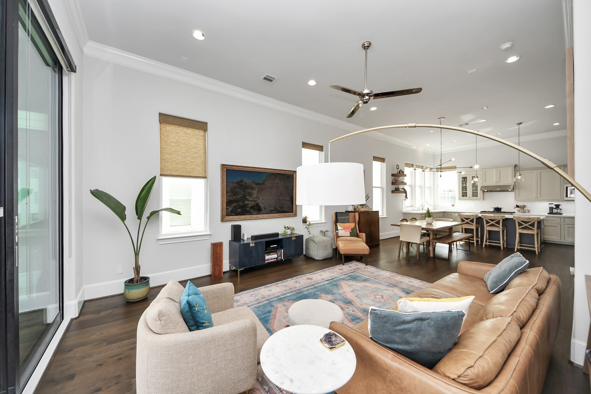 Spacious open-concept living area featuring a modern kitchen with a large island, cozy seating, elegant lighting, and expansive windows for ample natural light.