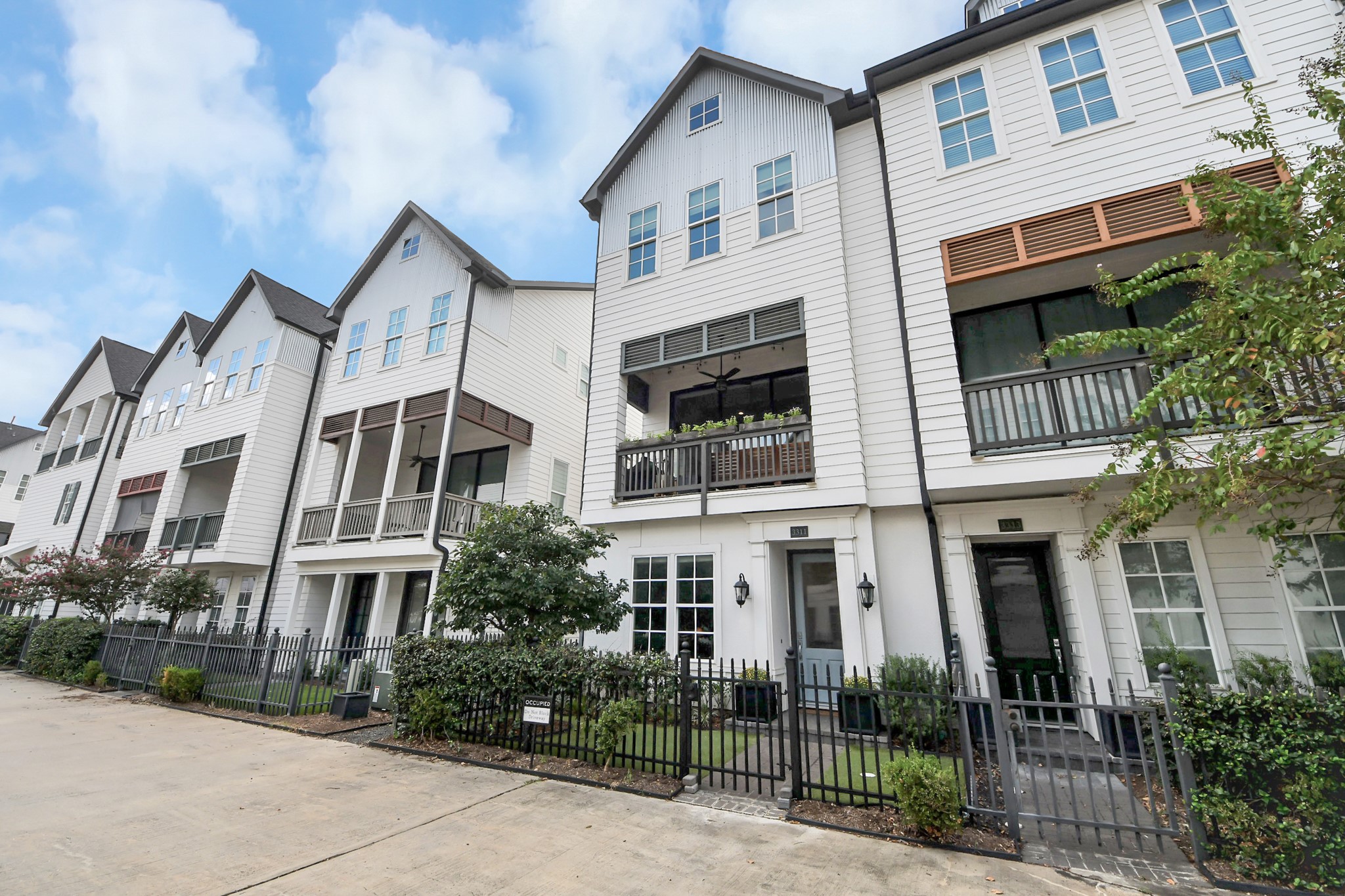 Charming row of modern townhouses with inviting balconies, stylish exteriors, and a neatly landscaped front.