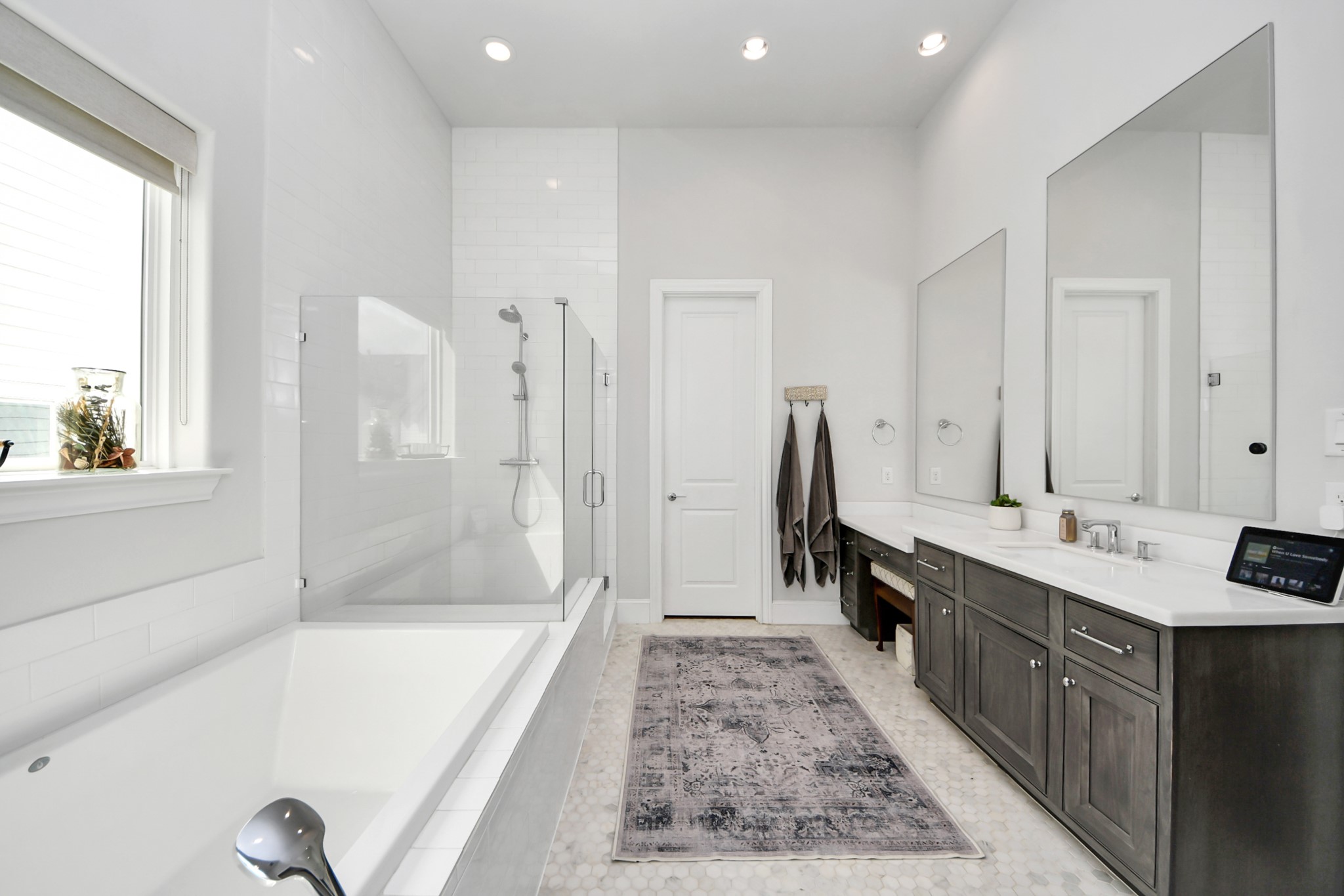Sleek and modern bathroom featuring a spacious glass-enclosed shower, a luxurious soaking tub, and dual-sink vanity with ample storage.