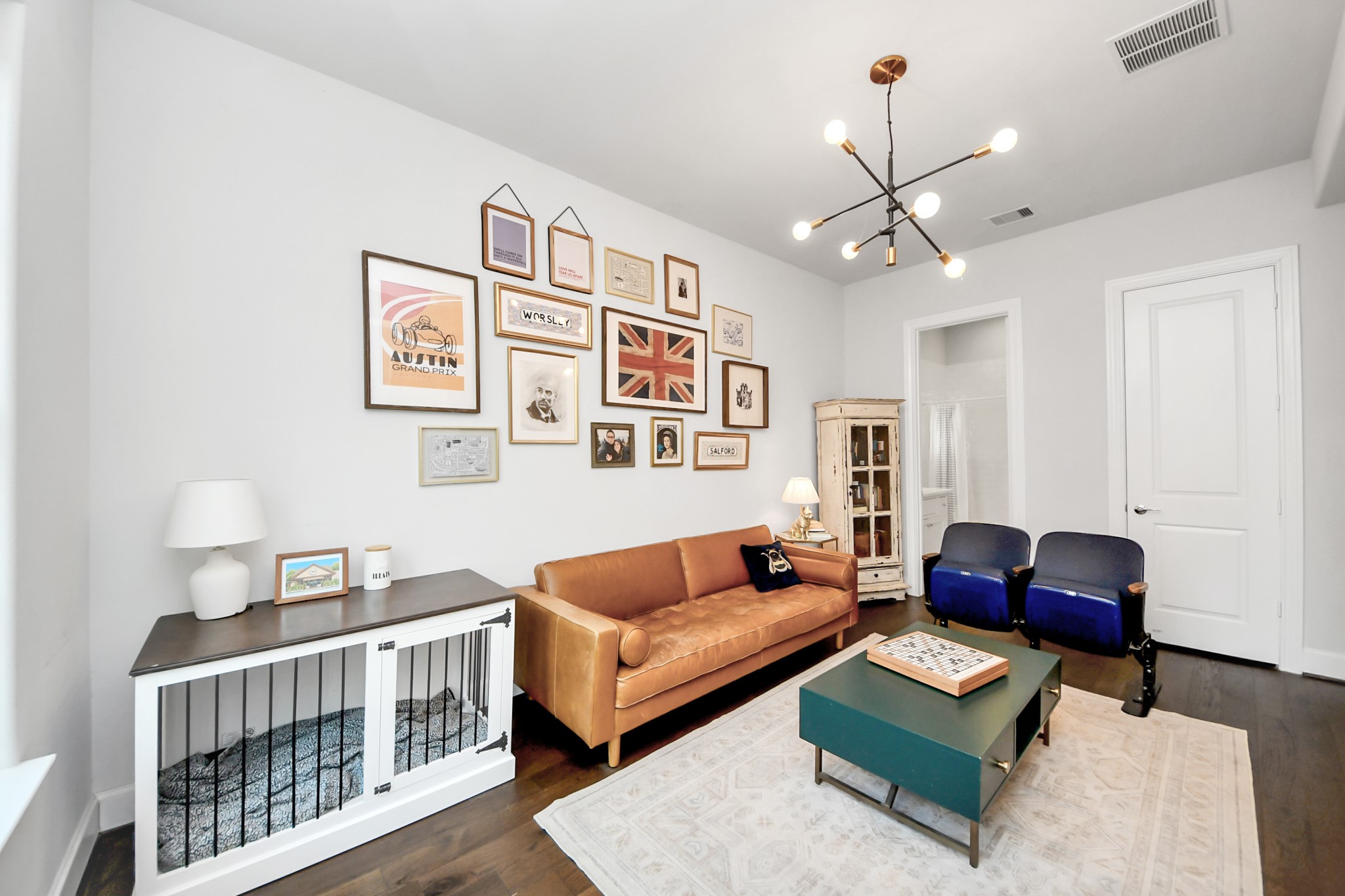 Charming living space featuring a cozy leather sofa, eclectic wall art, and a modern light fixture, complemented by a stylish mix of seating and decor.