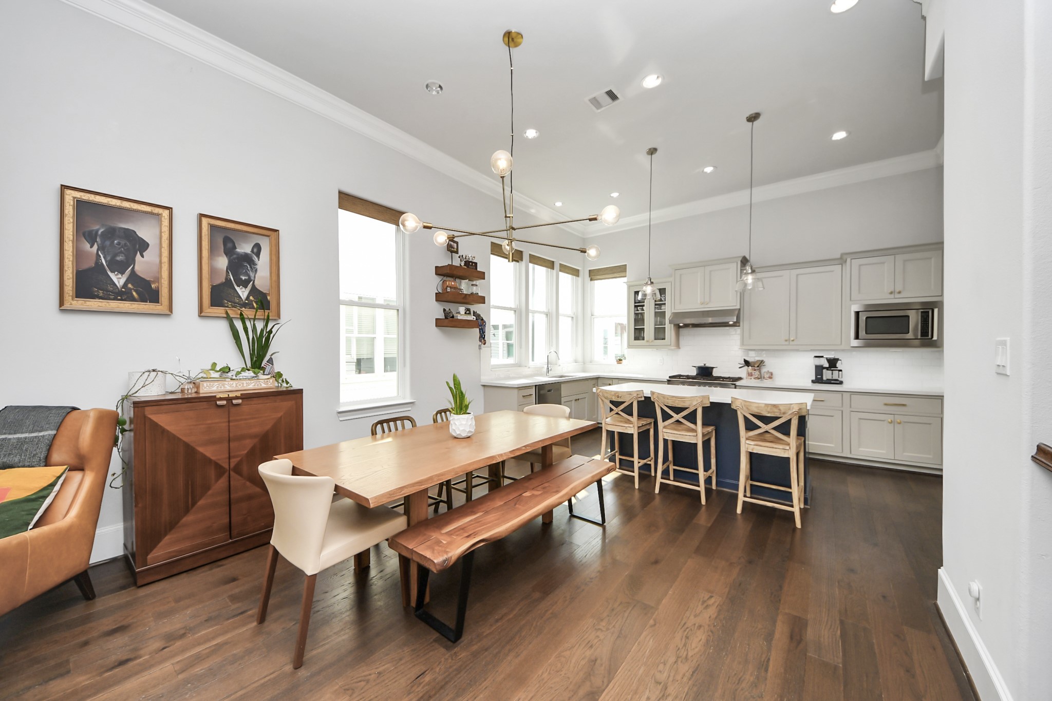 Elegant open-concept kitchen and dining area featuring white cabinetry, a spacious island with seating, and modern lighting.