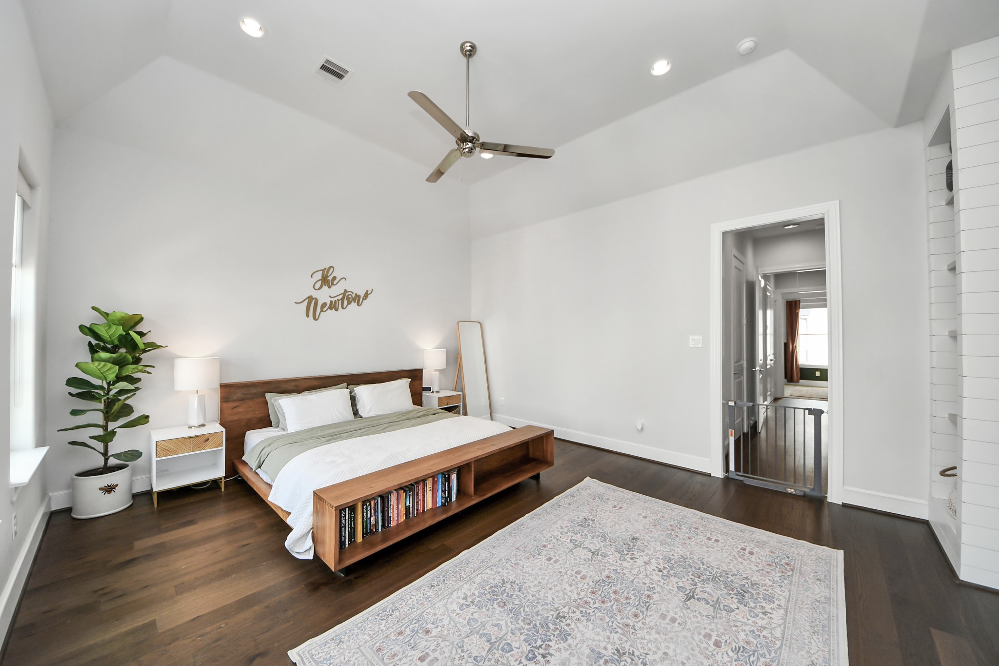 Spacious and inviting bedroom featuring a vaulted ceiling, sleek ceiling fan, and elegant hardwood floors. The room is accented with modern furnishings, a cozy rug, and ample natural light, creating a relaxing retreat.