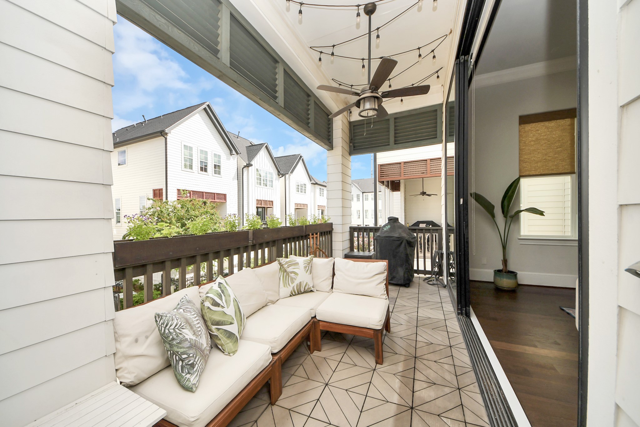 Charming covered patio with stylish tile flooring, cozy seating, and ceiling fan, perfect for outdoor relaxation and entertaining.