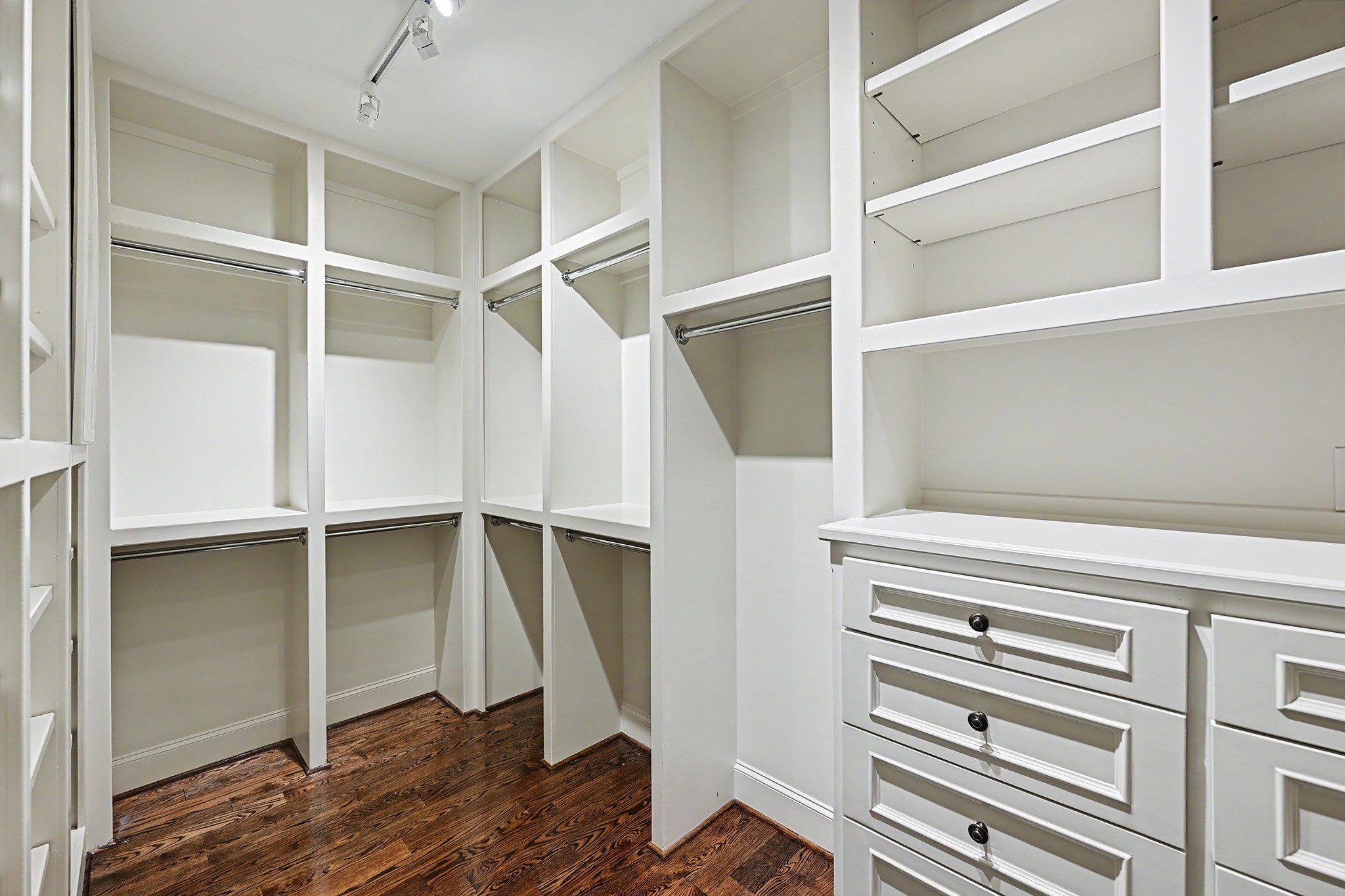 One of two primary suite walk-in closets, featuring extensive built-in cabinetry and ample hanging space for clothing, shoes, and accessories.