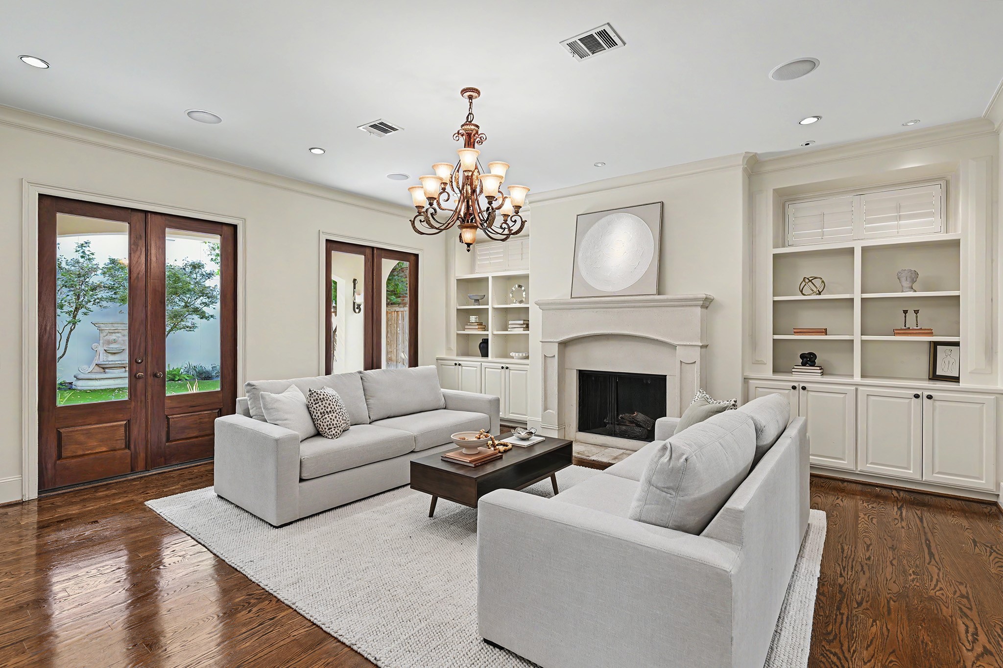 The spacious family room allows for versatile furniture arrangements and features a fireplace flanked by custom built-in shelving and cabinetry. French doors open to the covered patio and backyard.