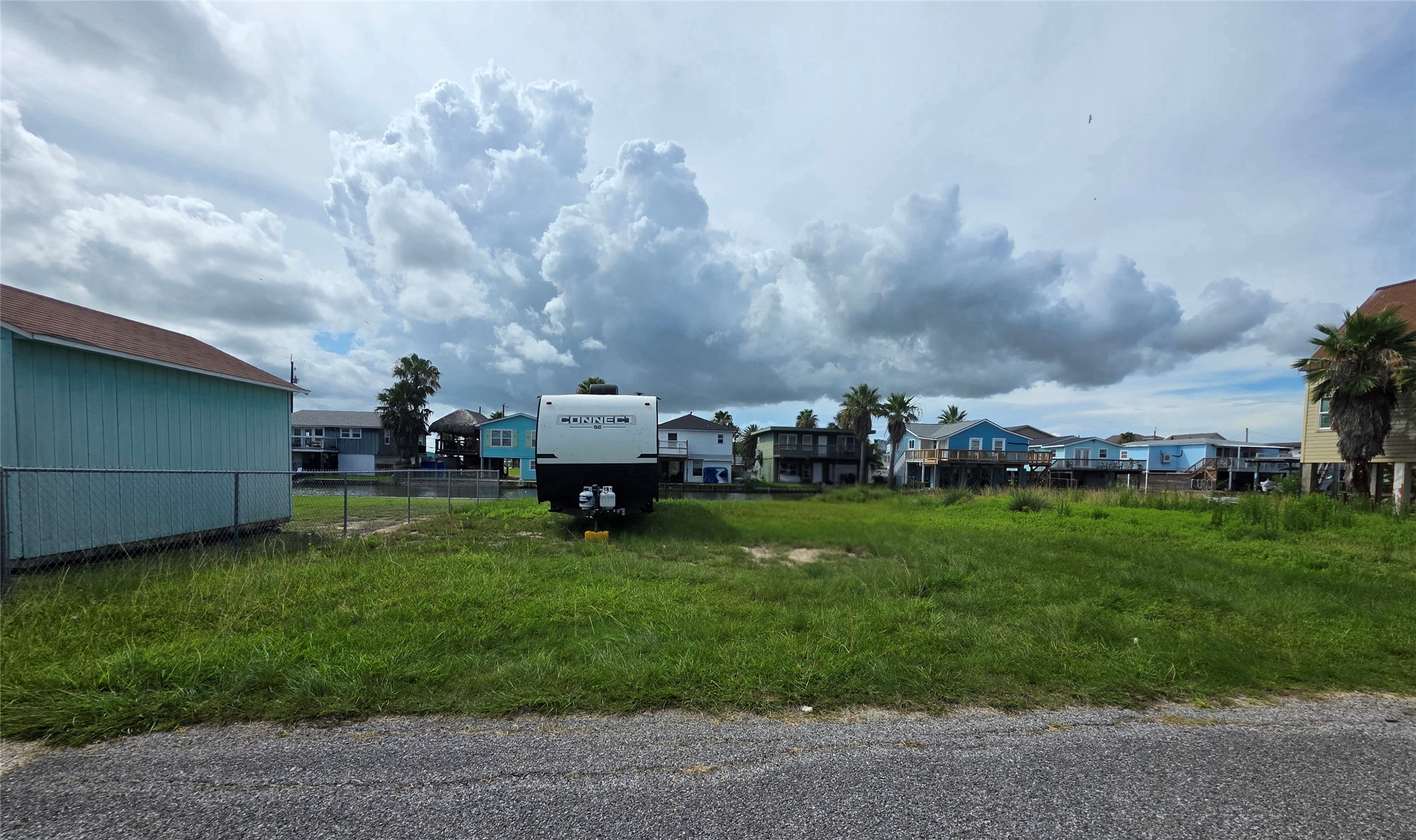 Prime Bayou Vista lot surrounded by charming waterfront homes and stunning coastal skies, offering the perfect setting for relaxed coastal living.