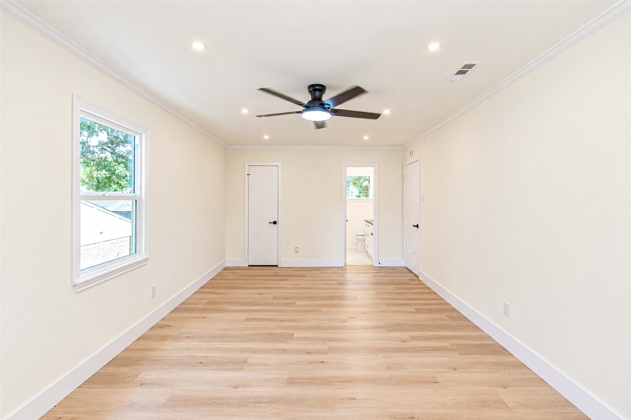 Experience the spacious elegance of Bedroom 3, featuring sleek vinyl floors, abundant natural light, and a modern ceiling fan for ultimate comfort.