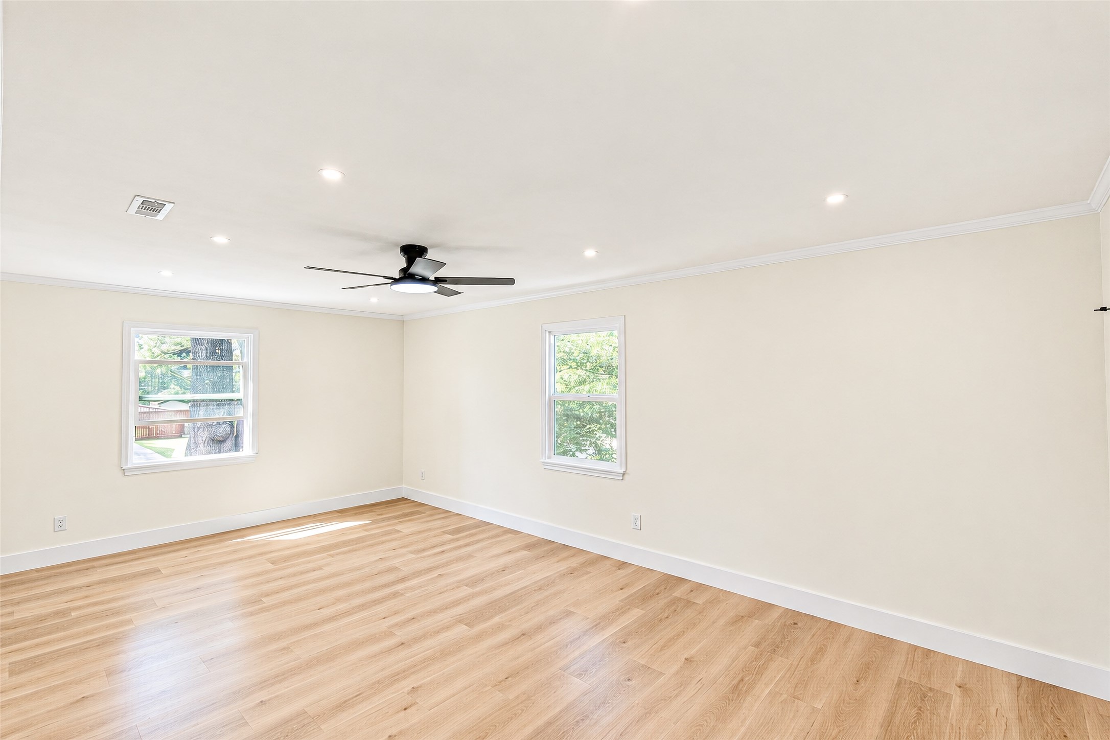 Bedroom 2 offers a bright and airy retreat with elegant vinyl floors, ample natural light, and a modern ceiling fan for comfort.