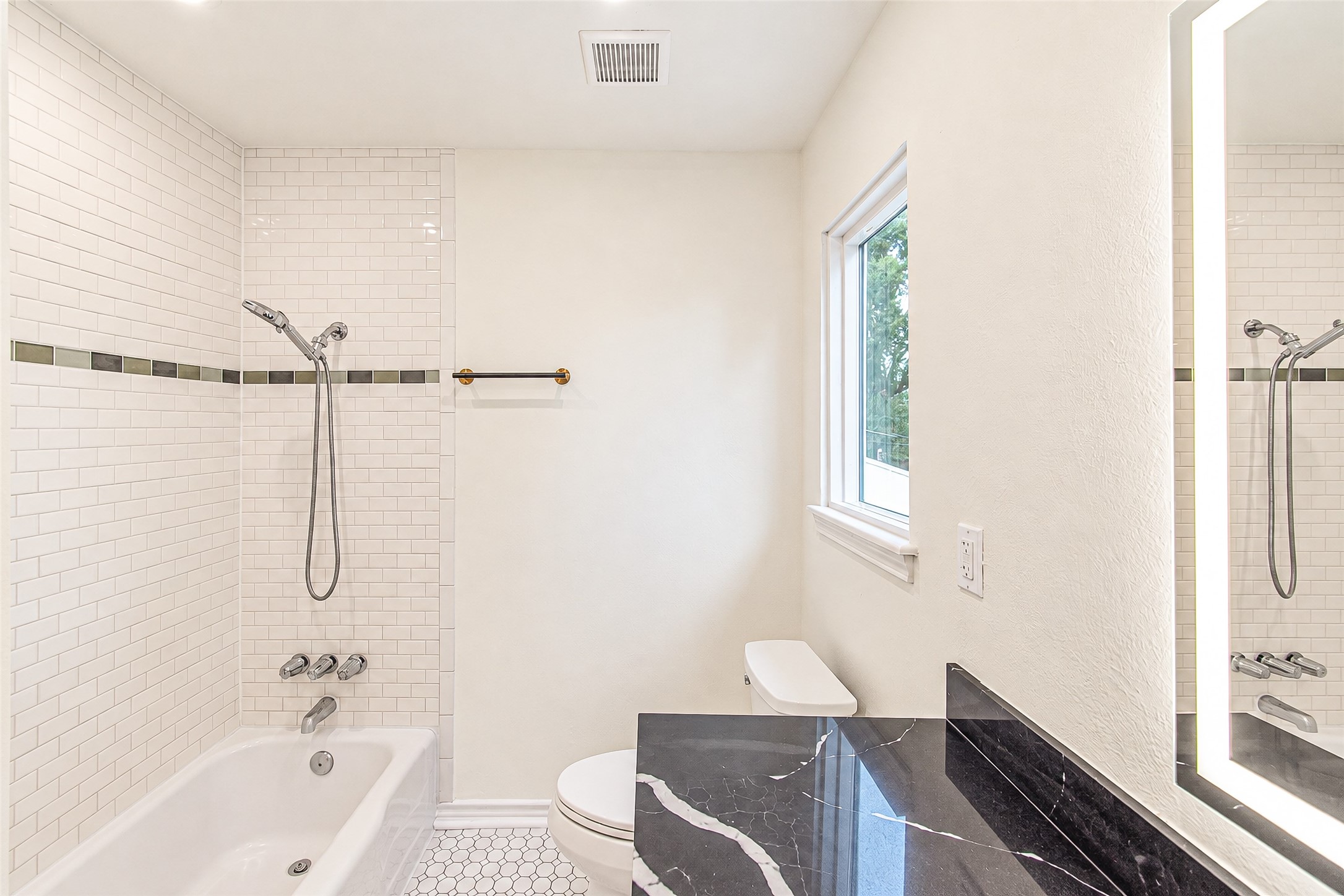 Experience luxury in the primary bath, featuring sleek subway tiles, a chic black quartz countertop, and abundant natural light for a serene retreat.