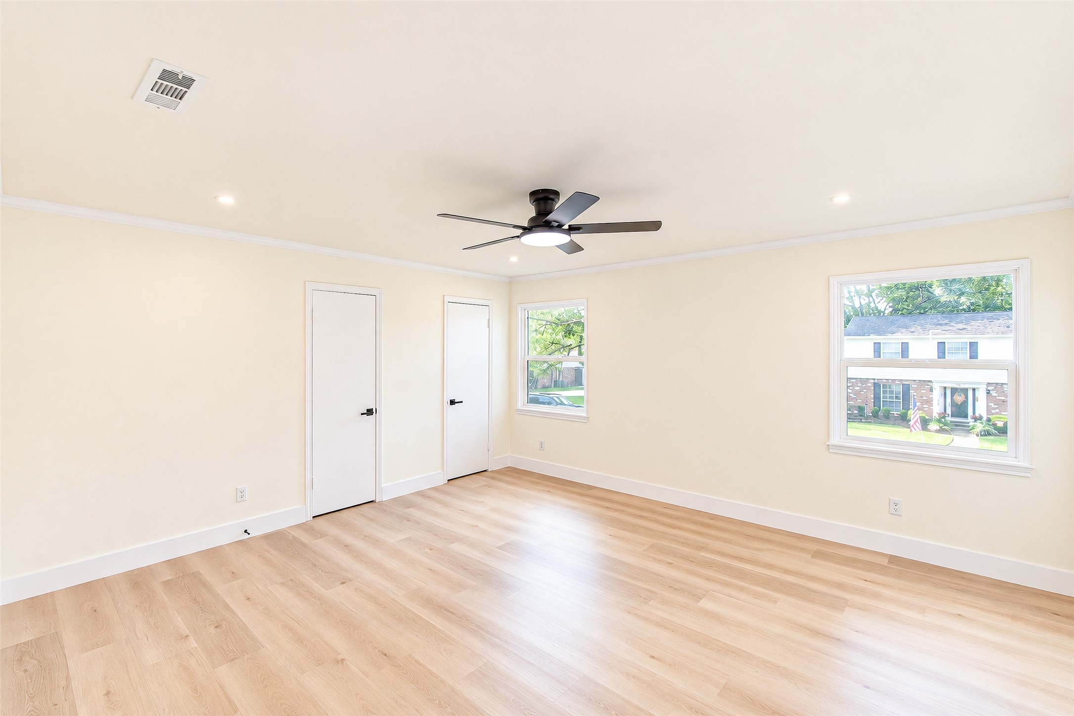 Spacious and sunlit, the primary bedroom offers sleek vinyl floors, fresh neutral walls, and large windows with views of the charming neighborhood.