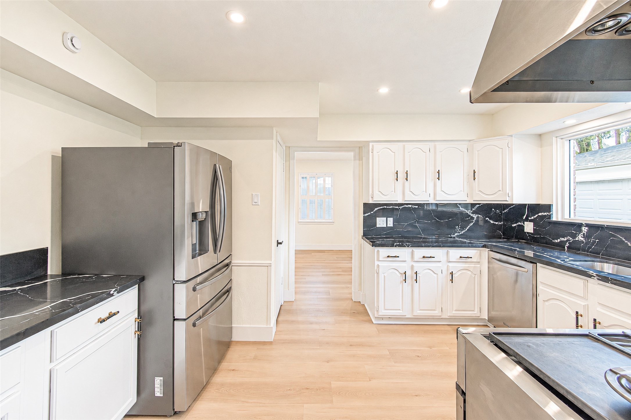 Bright kitchen with sleek stainless steel appliances, elegant black quartz countertops, and ample white cabinetry, offering a perfect blend of style and functionality.