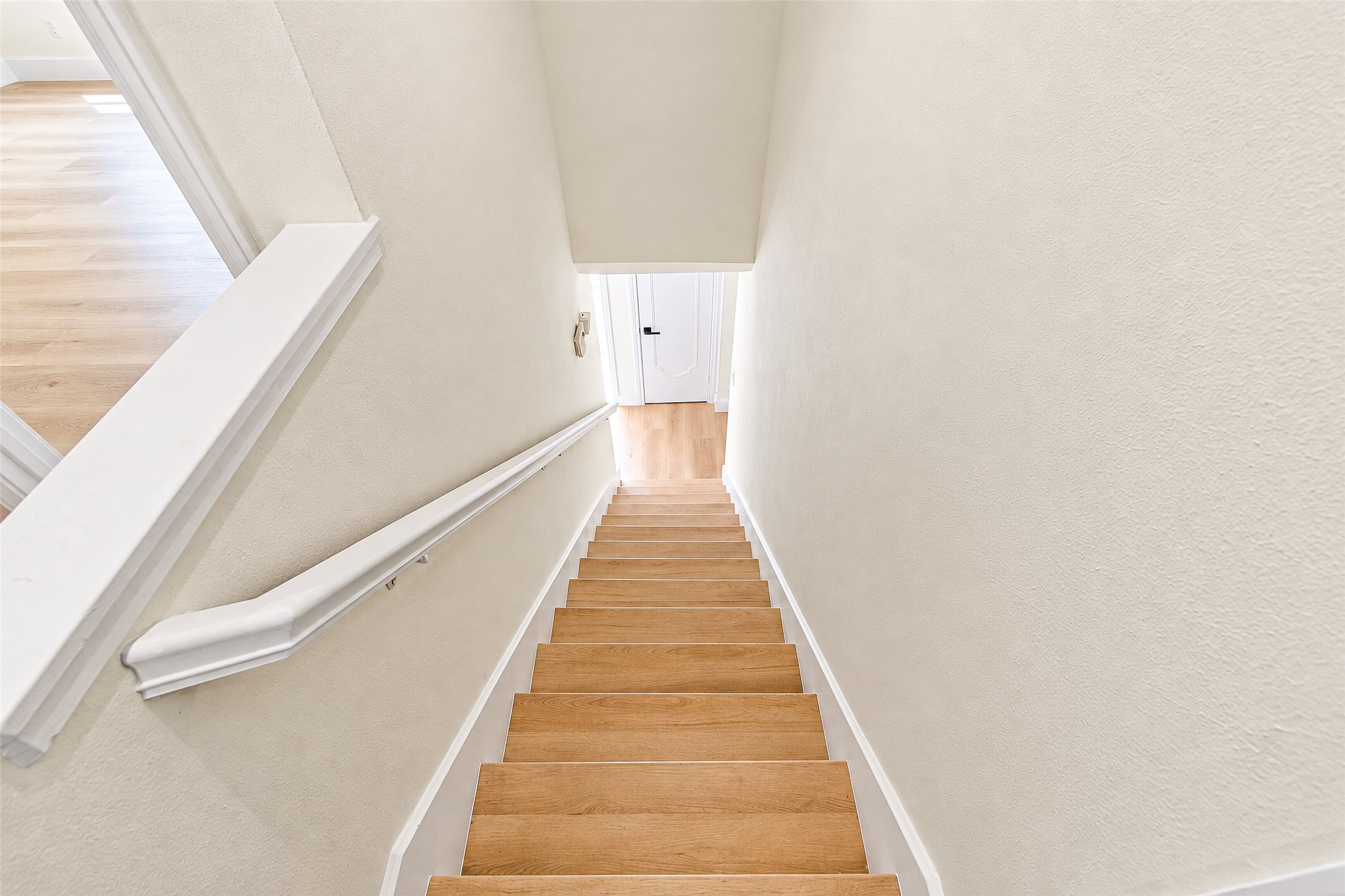 Bright, inviting staircase with sleek steps and crisp white walls leading to a lower level.