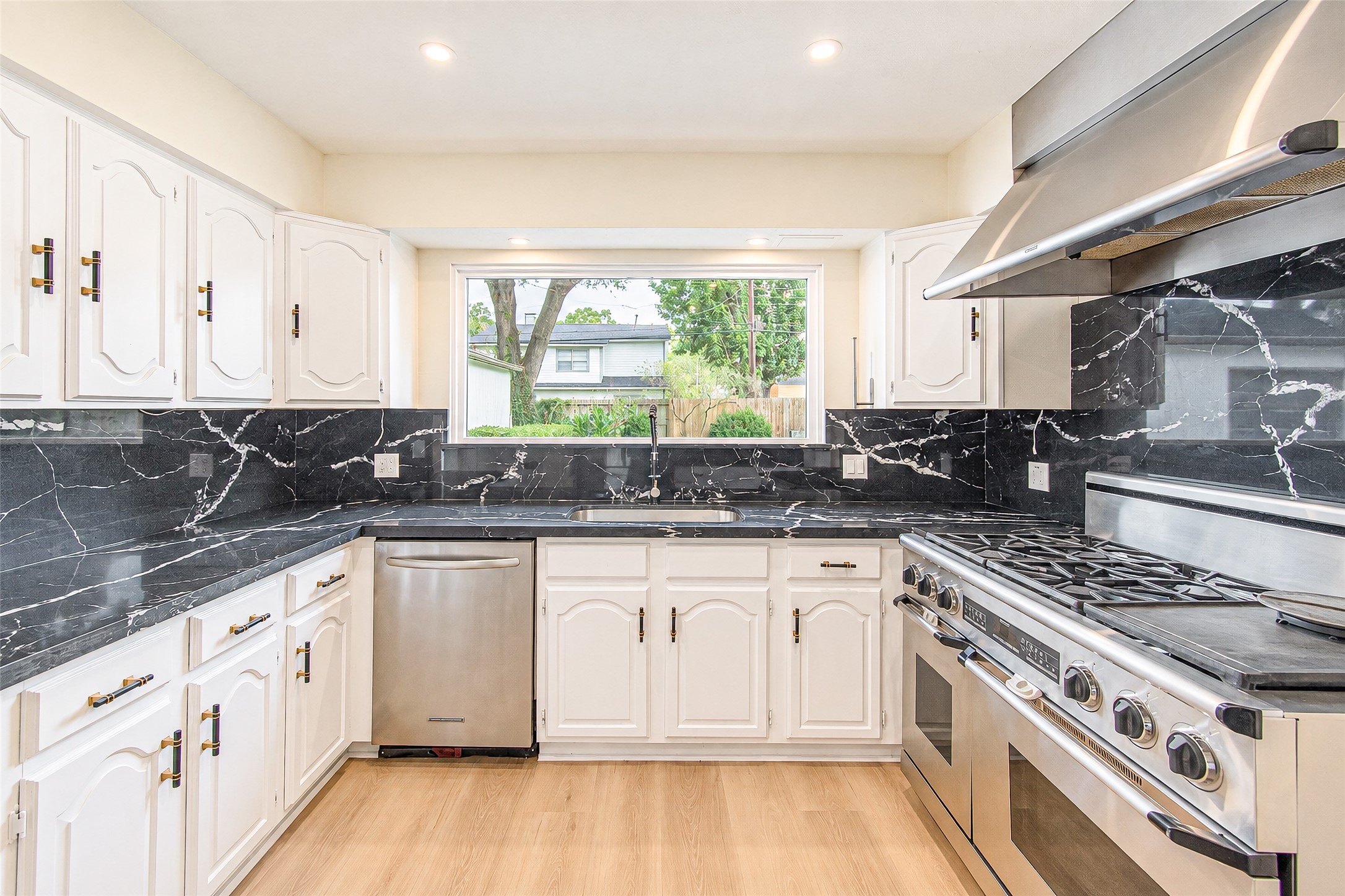 Modern kitchen featuring sleek black quartz countertops and backsplash, complemented by white cabinetry and high-end stainless steel appliances.