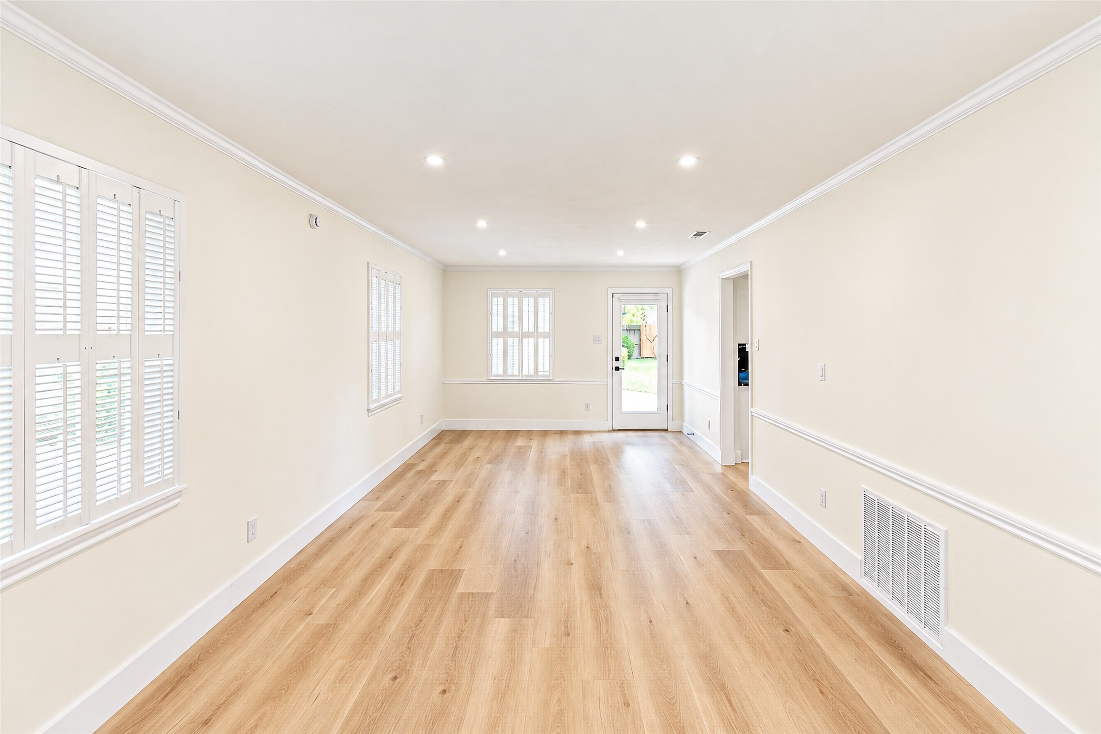 Bright and inviting, this spacious living room features elegant vinyl floors, abundant natural light, and seamless access to the outdoors through a stylish door.