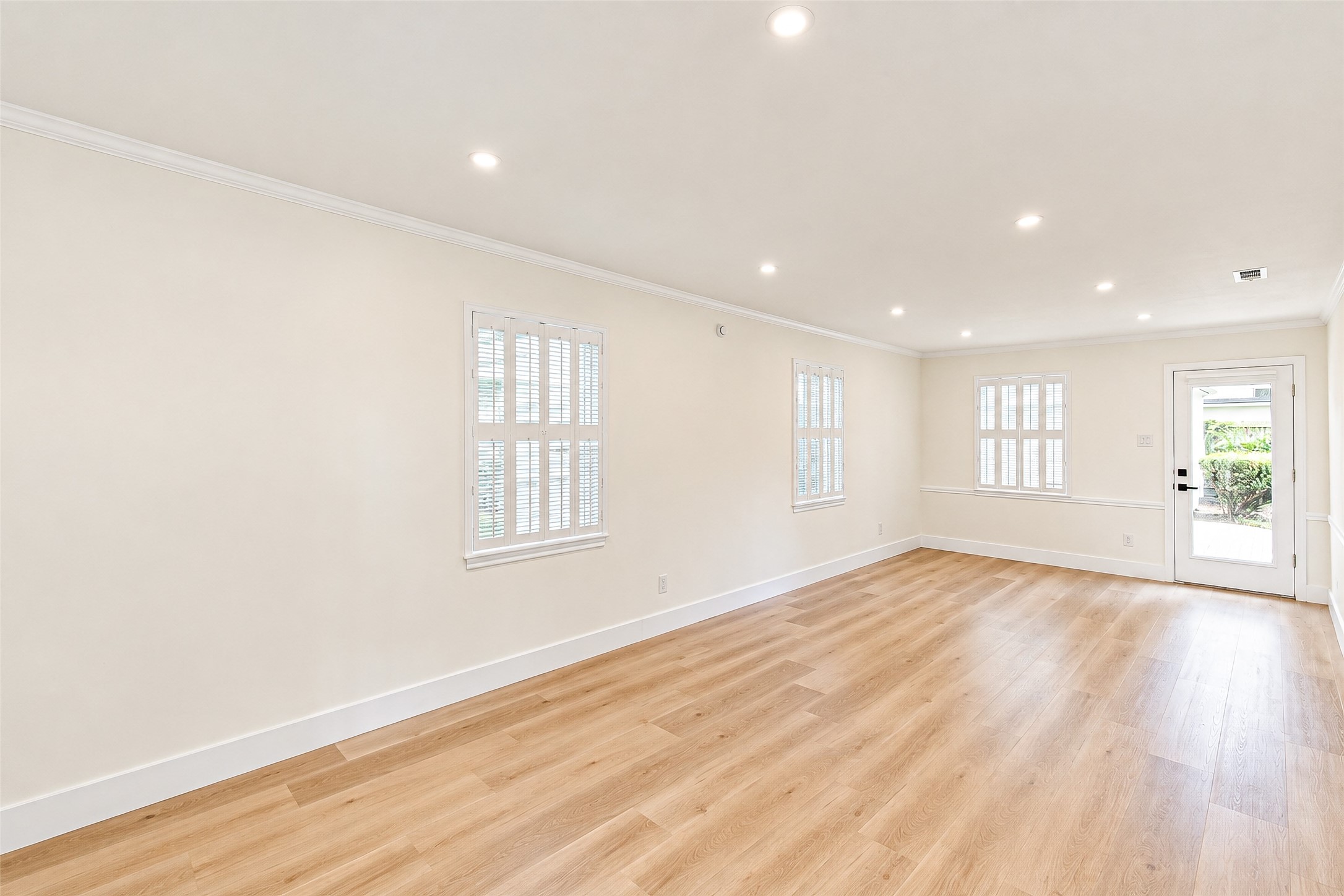 Bright and inviting, this spacious living room boasts elegant vinyl floors, abundant natural light, and seamless access to outdoor tranquility.