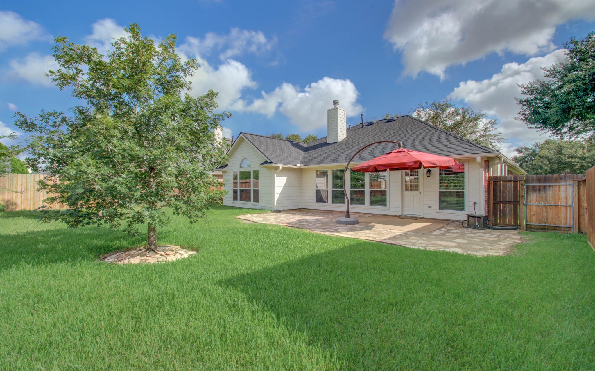 Charming backyard featuring lush green grass and mature trees for added privacy and shade.
