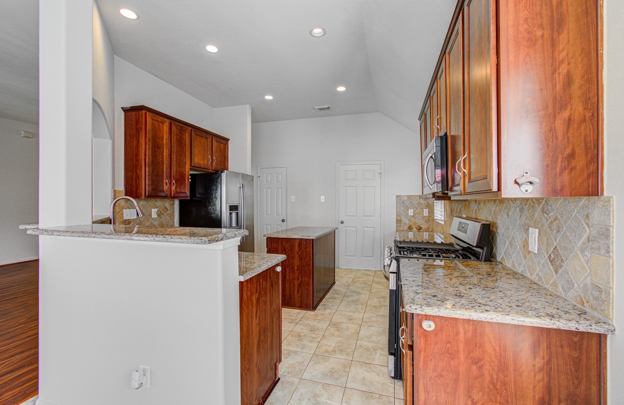 Gracious sized kitchen featuring elegant granite countertops, rich wood cabinetry, and modern stainless steel appliances, accented by a stylish tile backsplash.