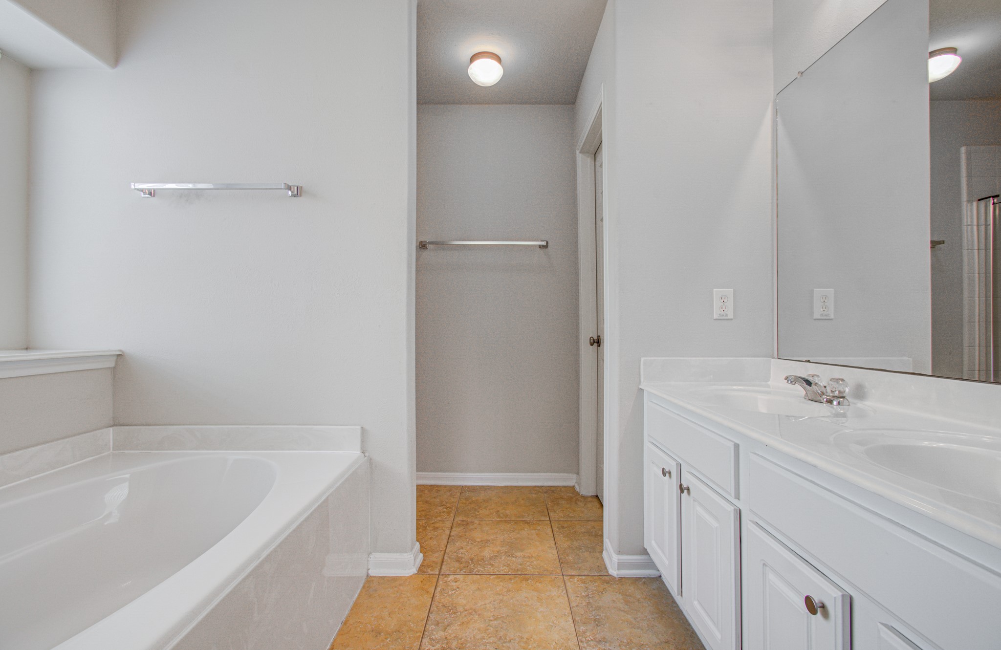 Primary bathroom features a luxurious soaking tub, dual-sink vanity, and elegant tile flooring for a serene retreat.