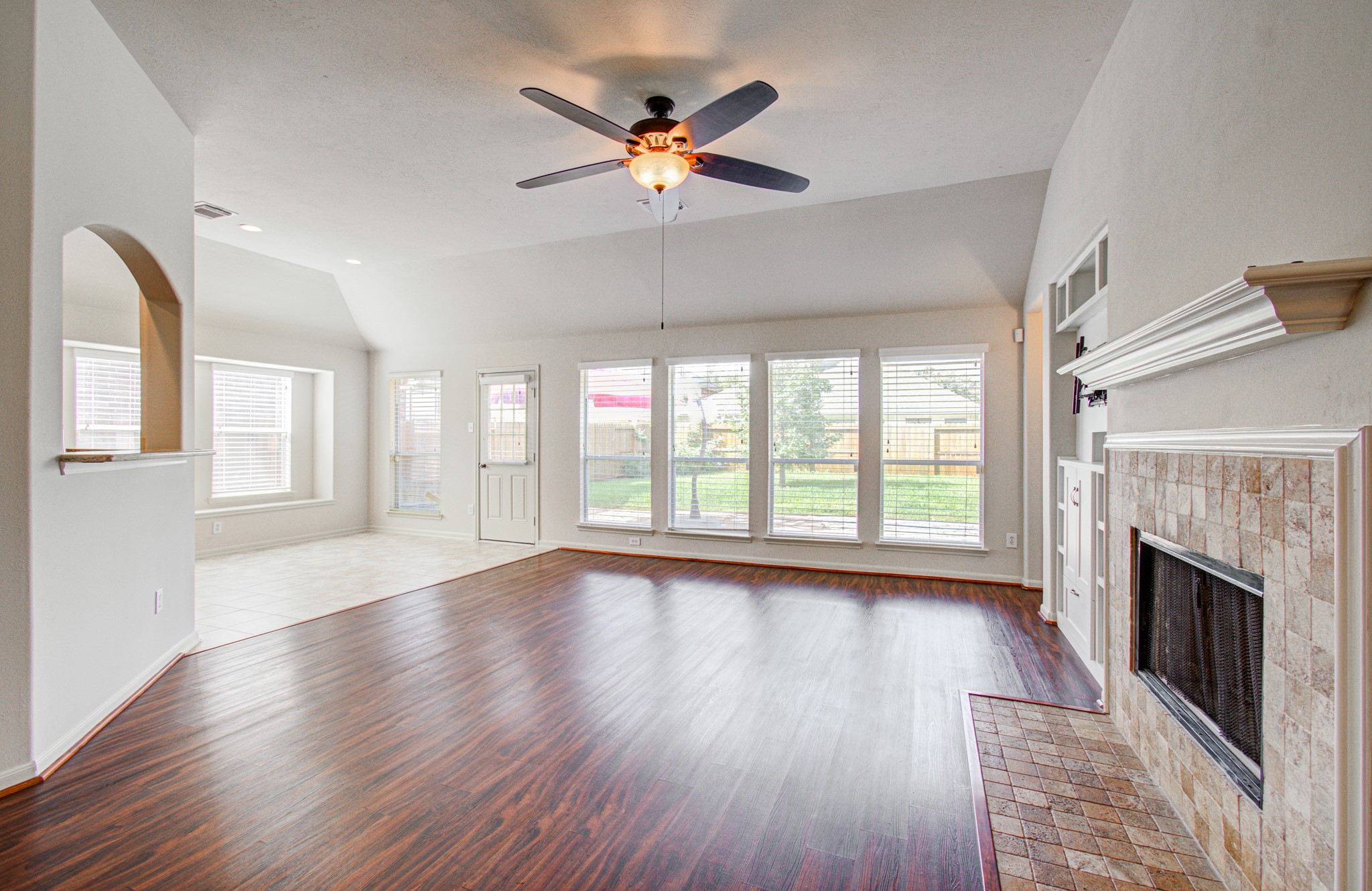 The spacious living area features a cozy fireplace and large windows offering abundant natural light and a view of the backyard.