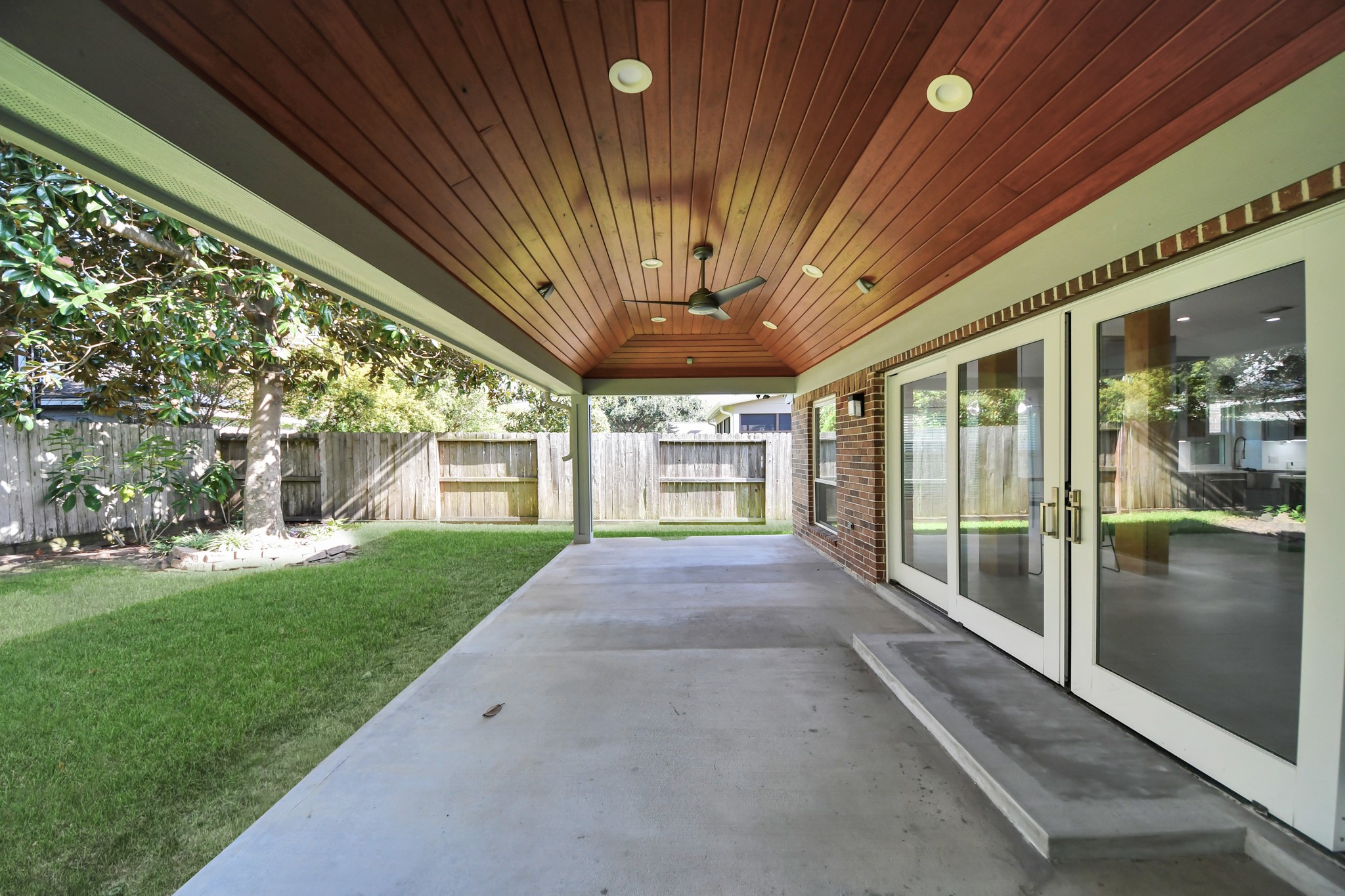 Right view of the spacious covered back patio with a luxurious wood ceiling and lights with a fan