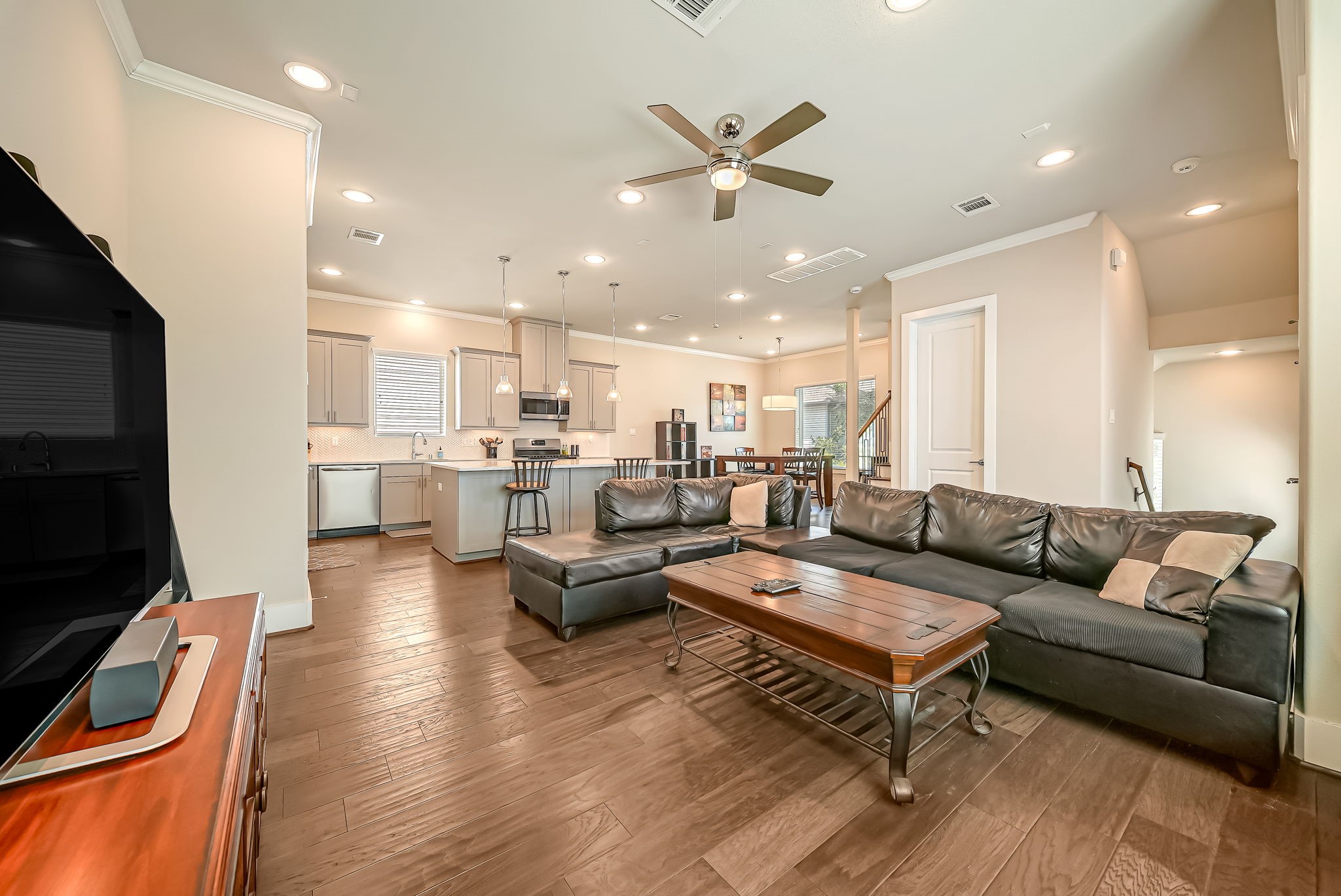 Bright living area with engineered hardwood flooring, crown molding, and generous natural light throughout.