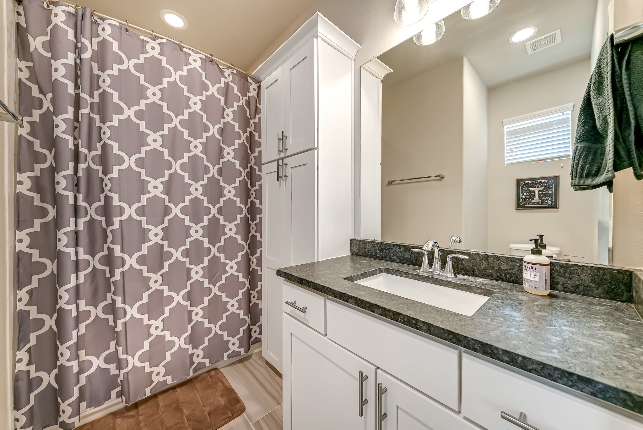 Secondary bathroom with quality finishes, generous storage, and stylish flooring.