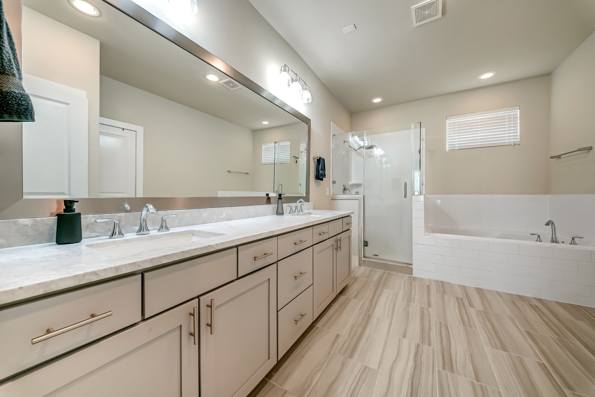 Spa-inspired primary bath featuring dual vanities, marble countertops, soft-close cabinetry, soaking tub, and separate shower.
