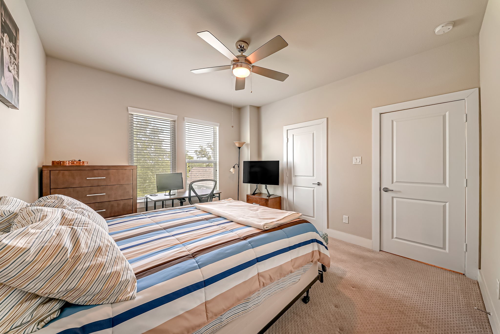Secondary bedroom with large windows, treetop views, and ample closet space.