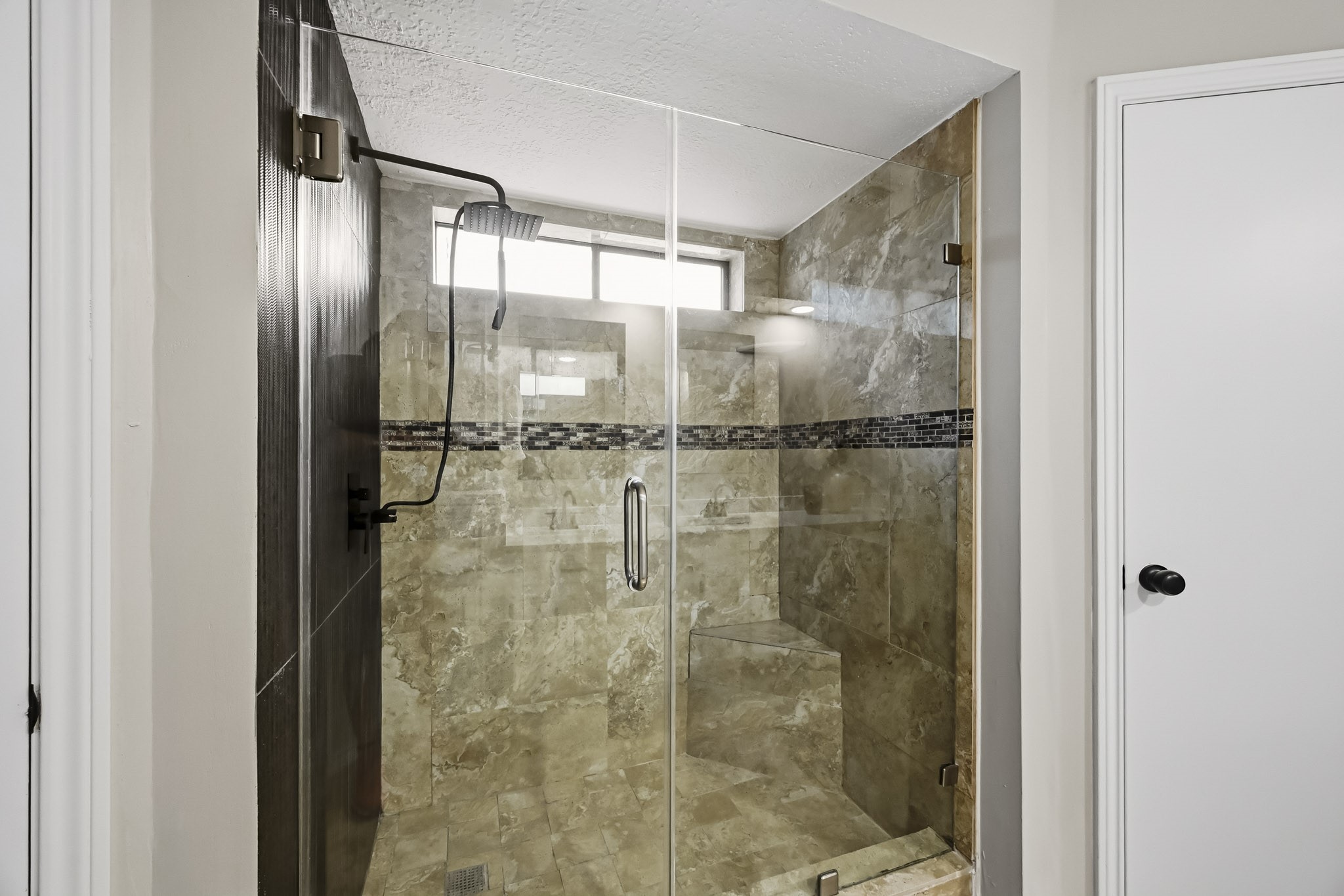 Luxurious walk-in shower with elegant tile work, a modern rain showerhead, and glass doors, offering a spa-like experience.