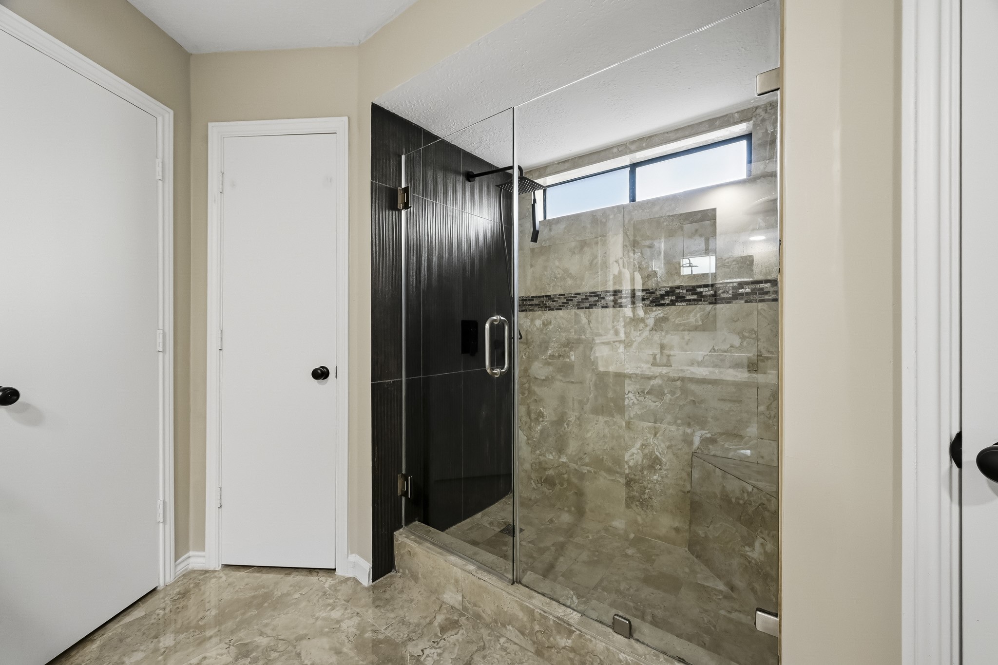 Elegant bathroom featuring a spacious glass-enclosed shower with modern tile work and ample natural light.