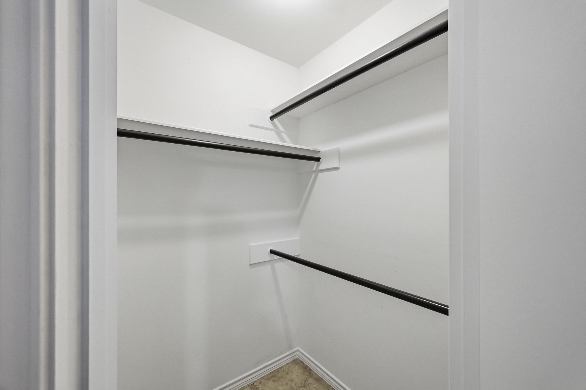Spacious walk-in closet with multiple hanging rods and bright lighting, perfect for organizing clothing and accessories.