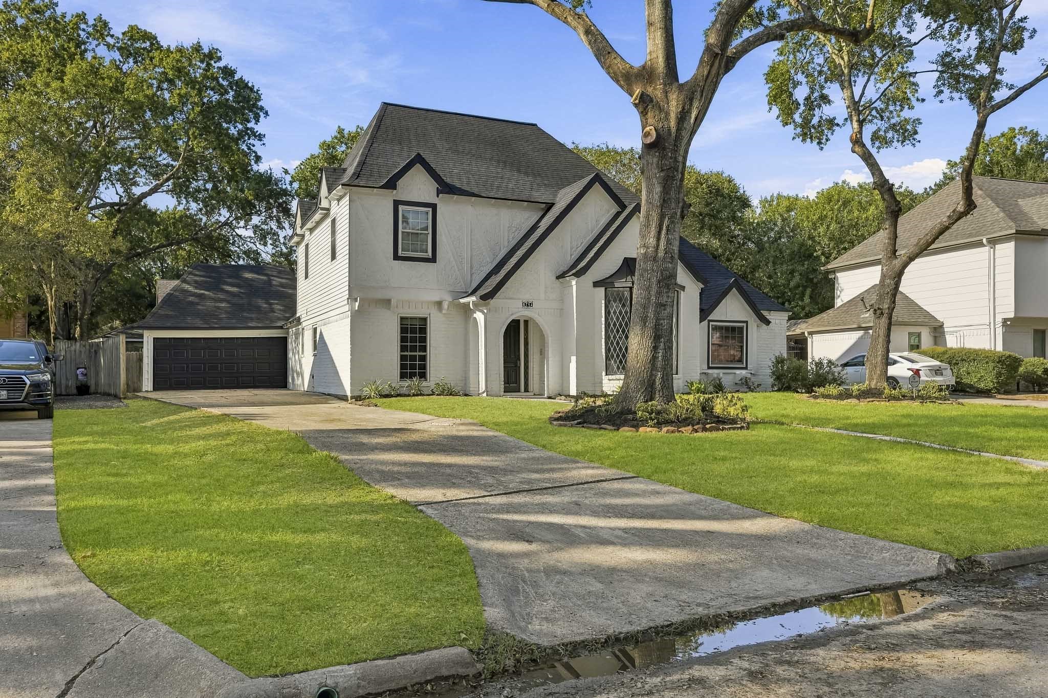 Featuring a spacious driveway, lush green lawn, and mature trees, offering excellent curb appeal in a serene neighborhood.