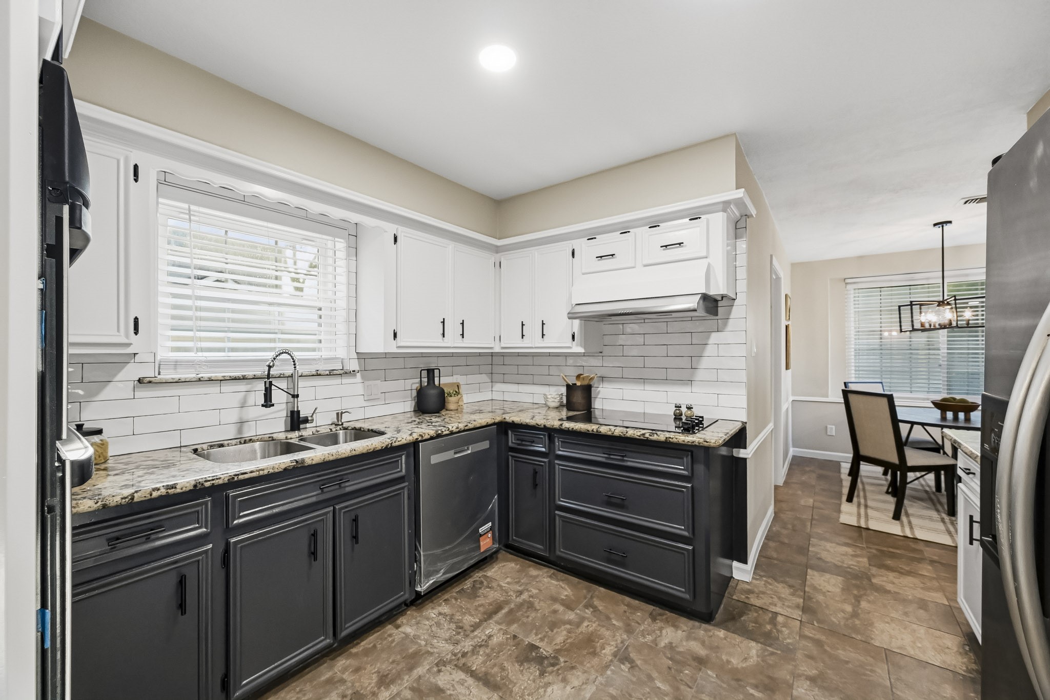 Charming kitchen with a sleek black-and-white color scheme, granite countertops, and modern stainless steel appliances, seamlessly connecting to a cozy dining area.