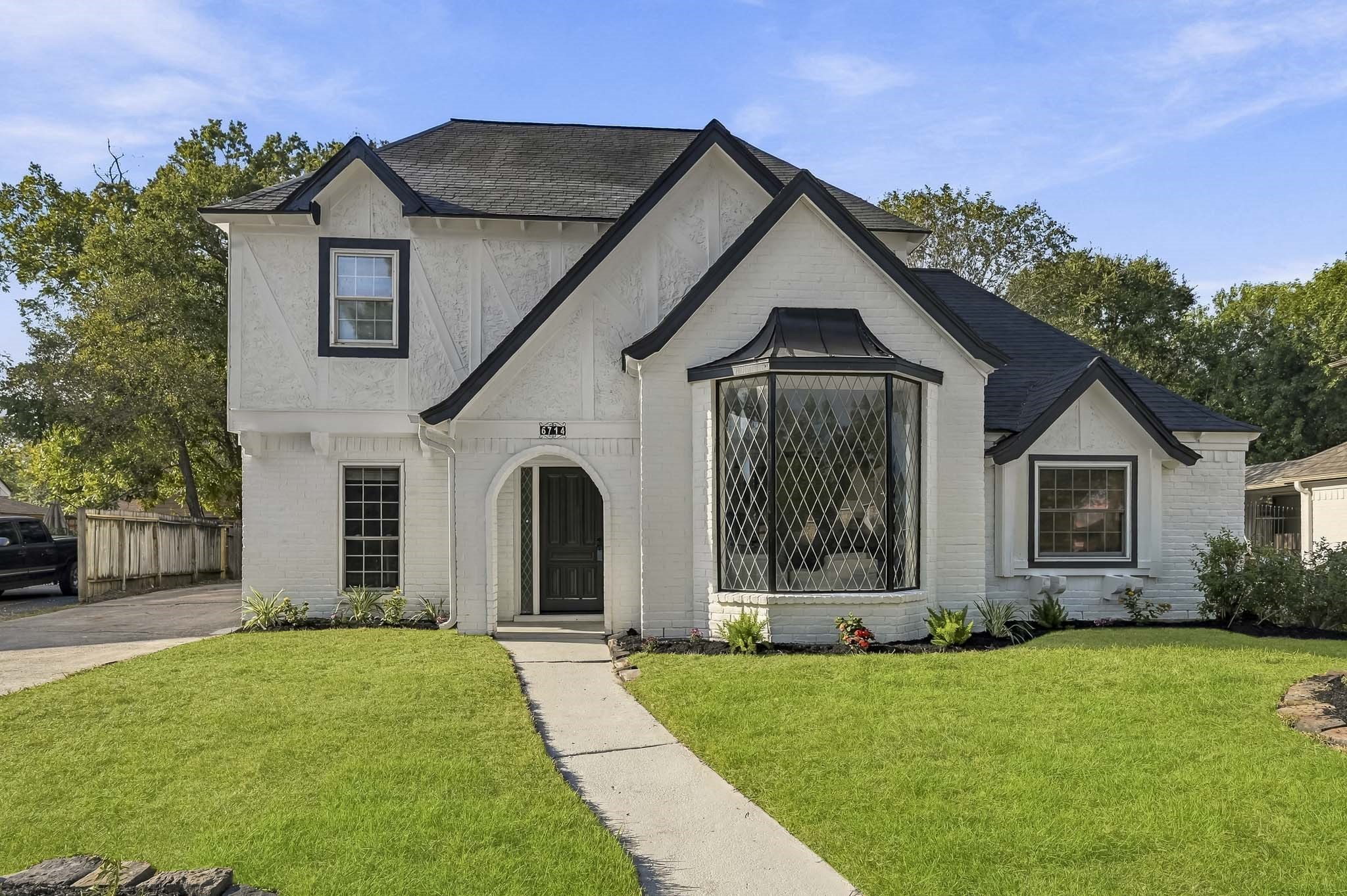 Charming two-story home with elegant Tudor-style architecture, featuring a distinctive bay window and inviting arched entryway, surrounded by a lush, manicured lawn. Charming two-story home with elegant Tudor-style architecture, featuring a distinctive bay window and inviting arched entryway, surrounded by a lush, manicured lawn.