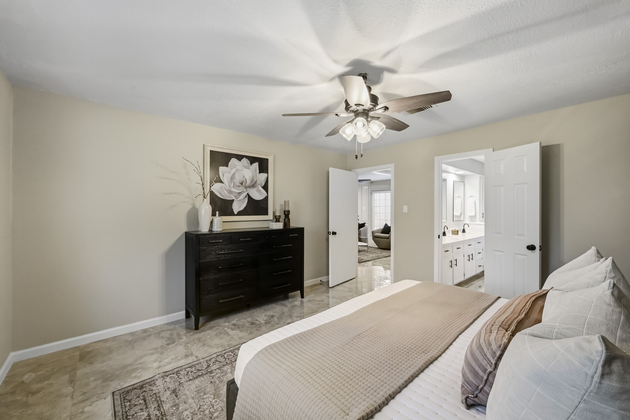 Elegant bedroom featuring a neutral palette with a ceiling fan, spacious layout, and an en-suite bathroom.