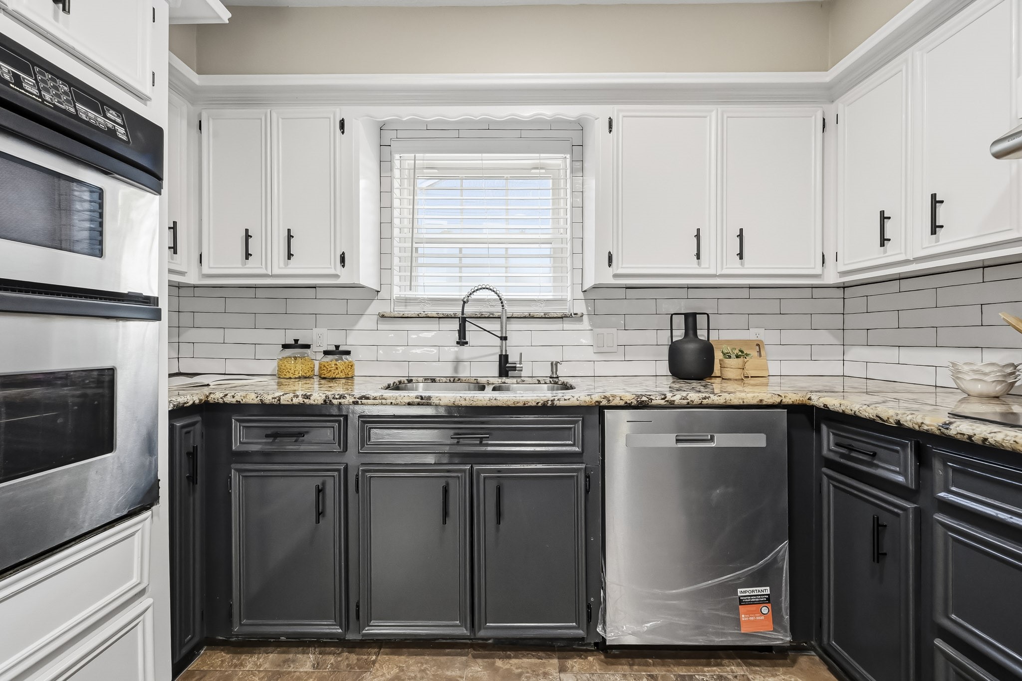 Charming kitchen with a sleek black and white color scheme, featuring granite countertops, stainless steel appliances, and ample cabinet space.