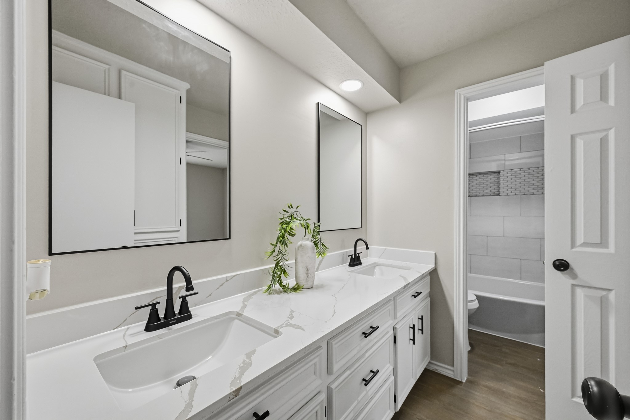 Modern bathroom featuring a sleek double vanity with marble countertops, stylish black fixtures, and ample cabinet space.
