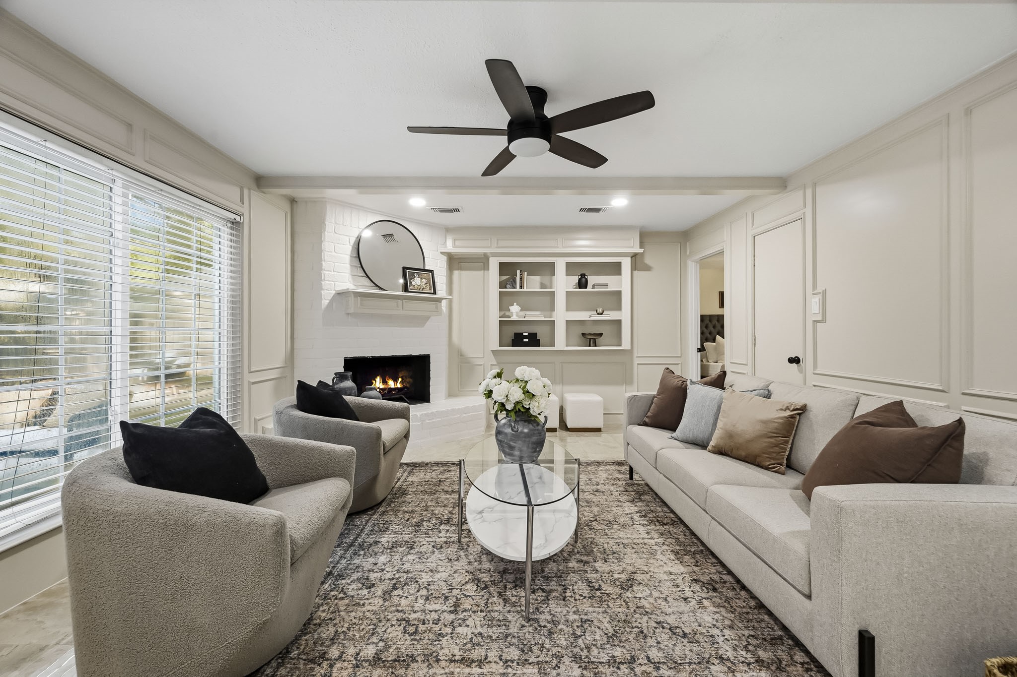 Elegant living room featuring a cozy fireplace, built-in shelving, and abundant natural light, perfect for relaxation and entertaining.