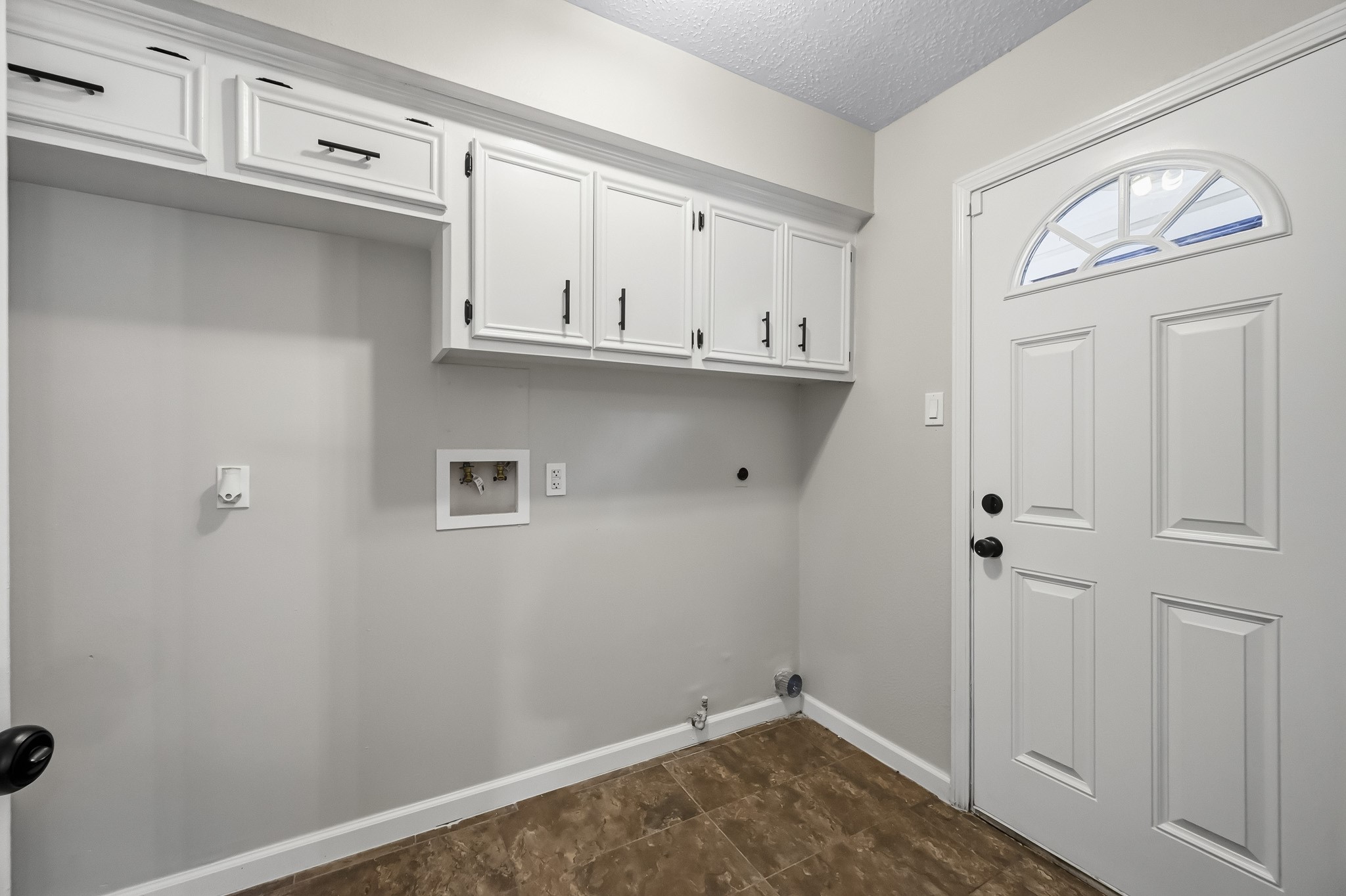 Bright and functional laundry room with ample cabinet storage and convenient utility hookups, complemented by a classic door design.