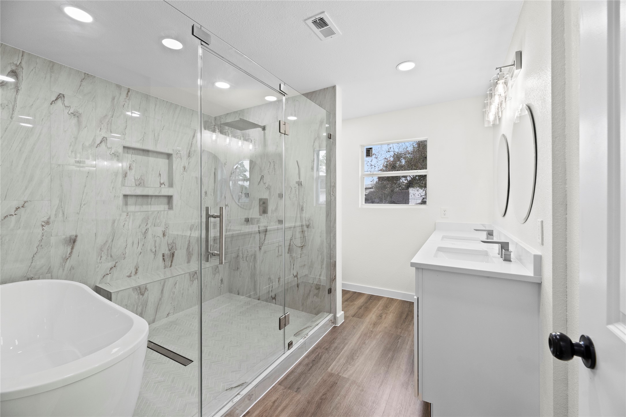 Gorgeous primary bathroom features a walk-in wet room with shower and soaking tub.